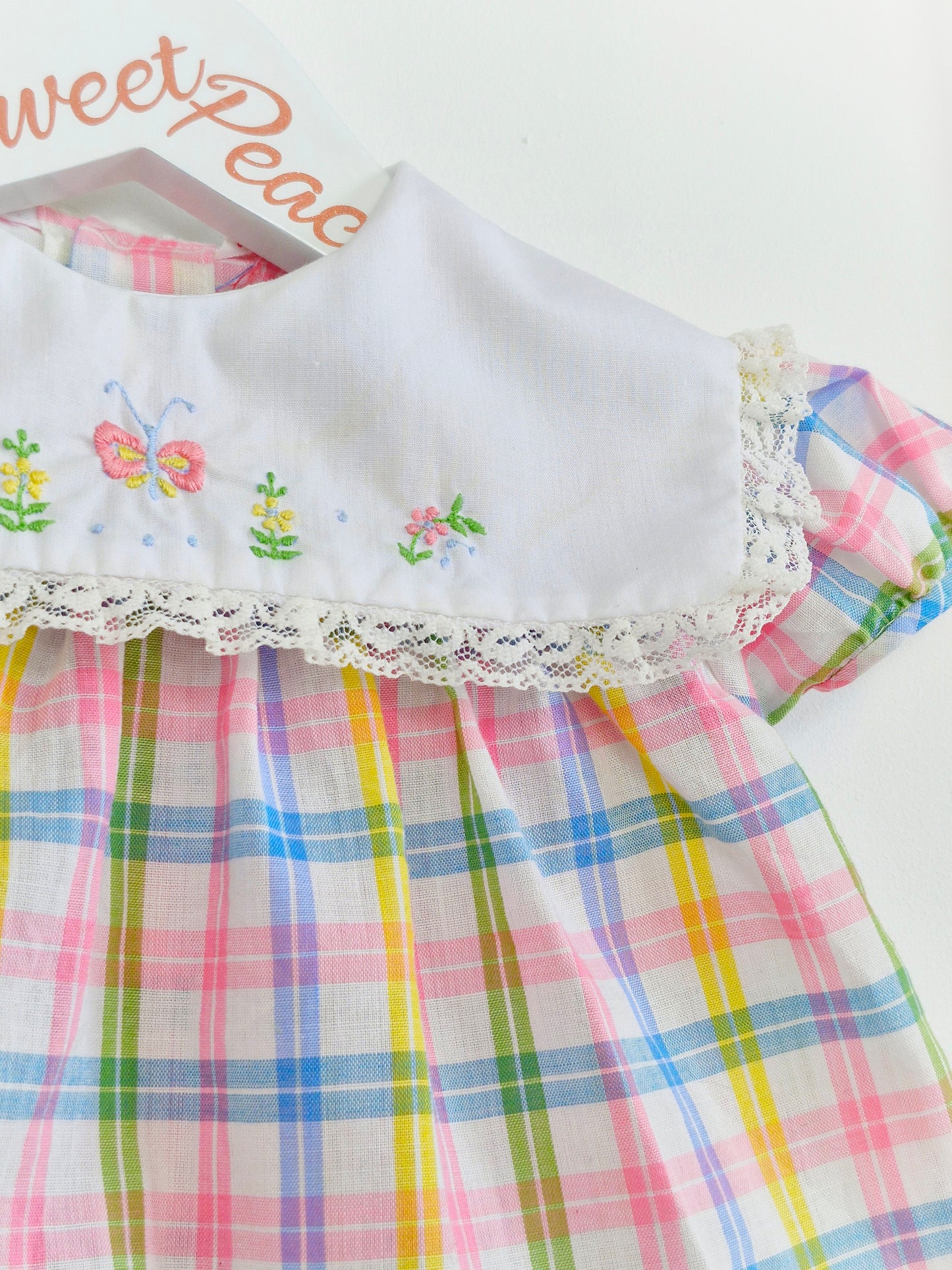 0-3 months. Pastel checked vintage baby dress with white bib, embroidered with flowers and a butterfly