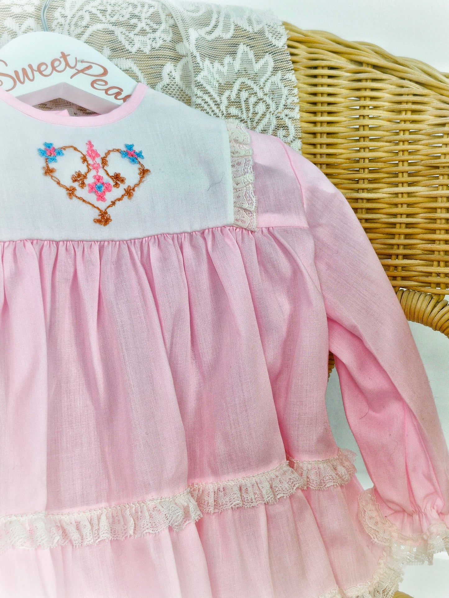 6-9 months. Pink Miniworld deess with white embroidered bib