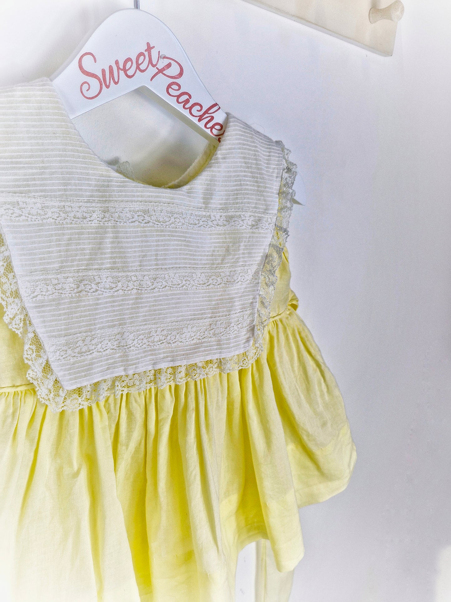 12-18 months. Lemon sleeveless dress with white bib