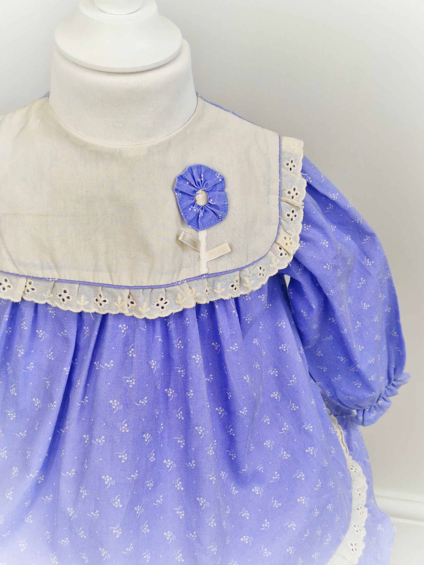 2 years. Blue Mini Togs dress with white bib and flowers