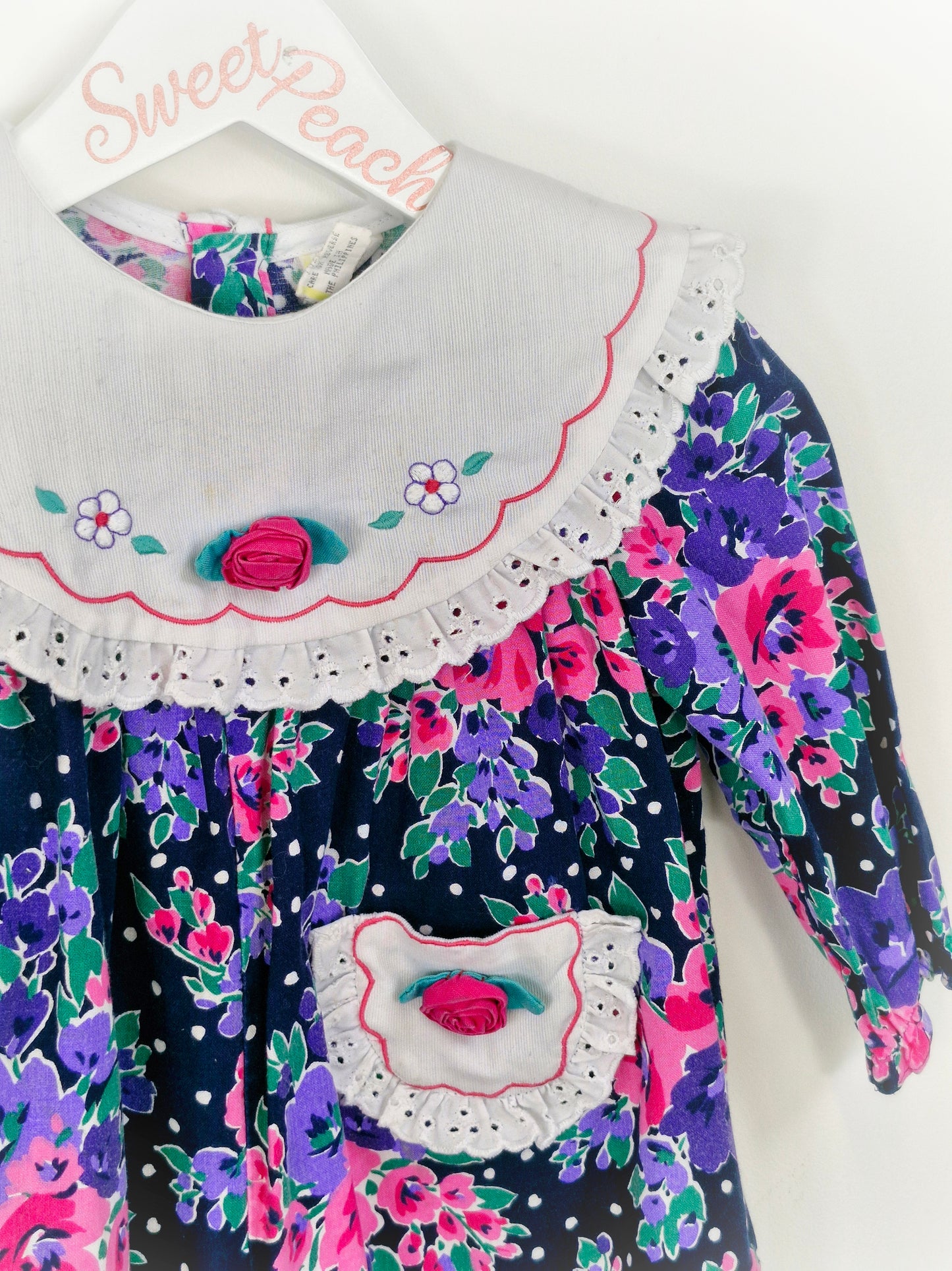 Best fit 18 months. Floral romper with embroidered white bib and pocket