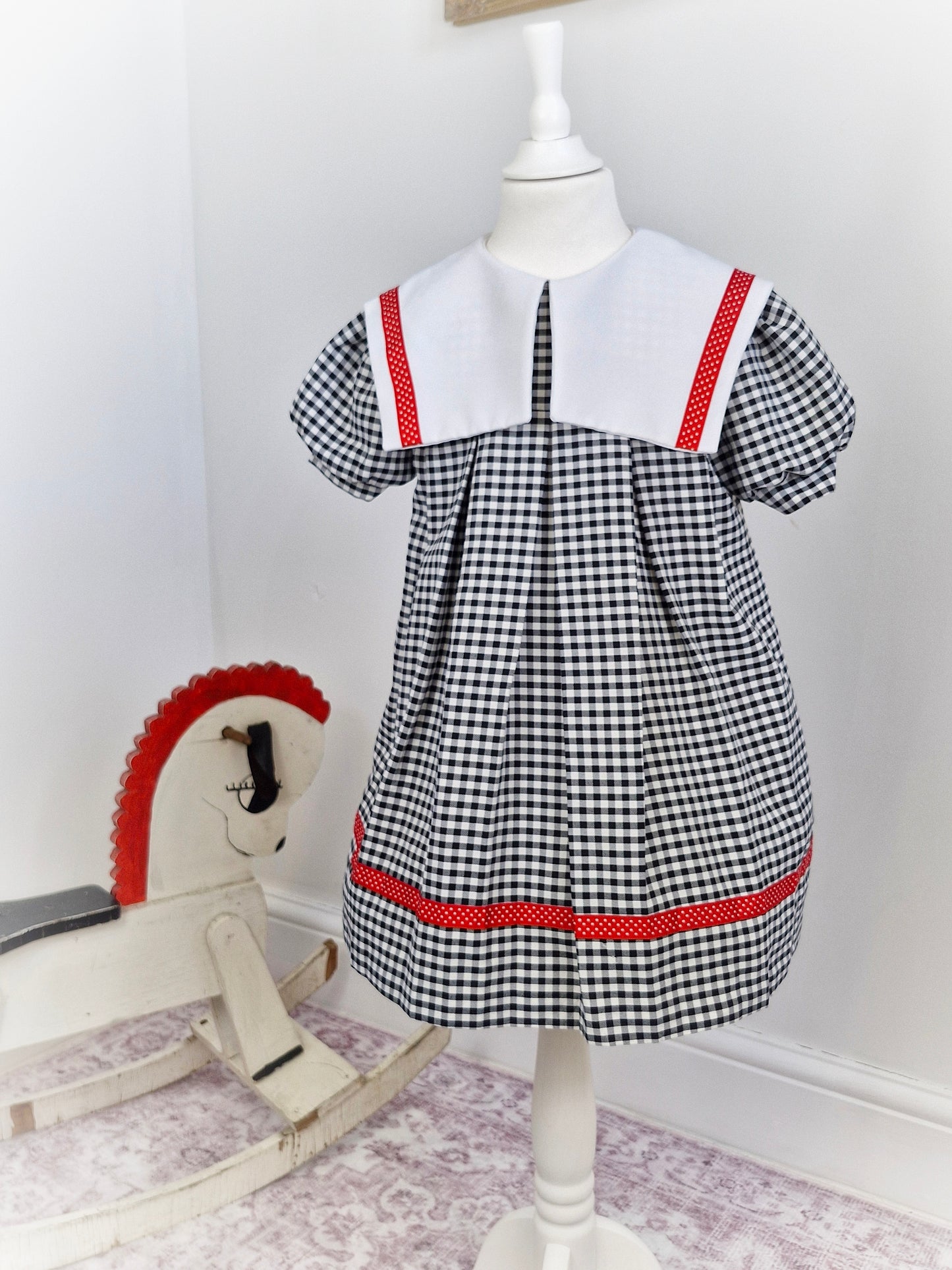 5-6 years. Black and white gingham dress with red ribbon trim and white bib