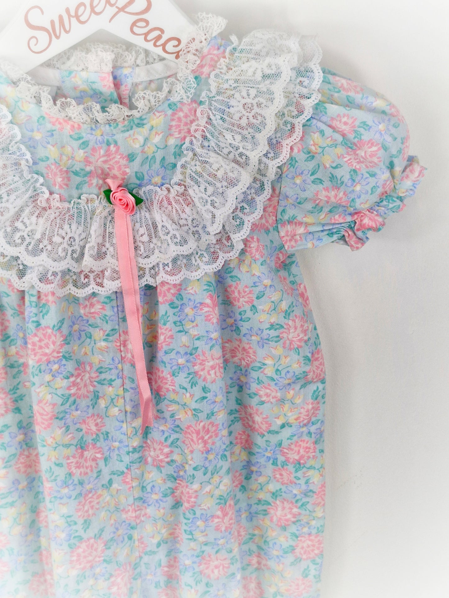 12 months. Pastel floral JoLene romper with lace frills and pink ribbon