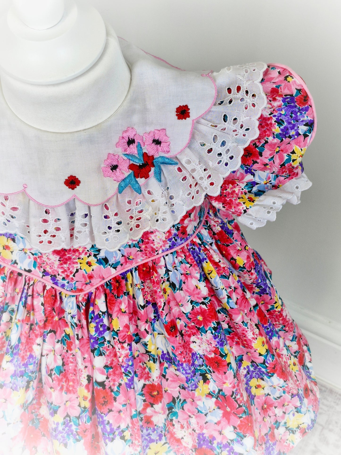 2 years. Ruth of Carolina pink floral vintage dress with white bib embroidered with flowers and lace details