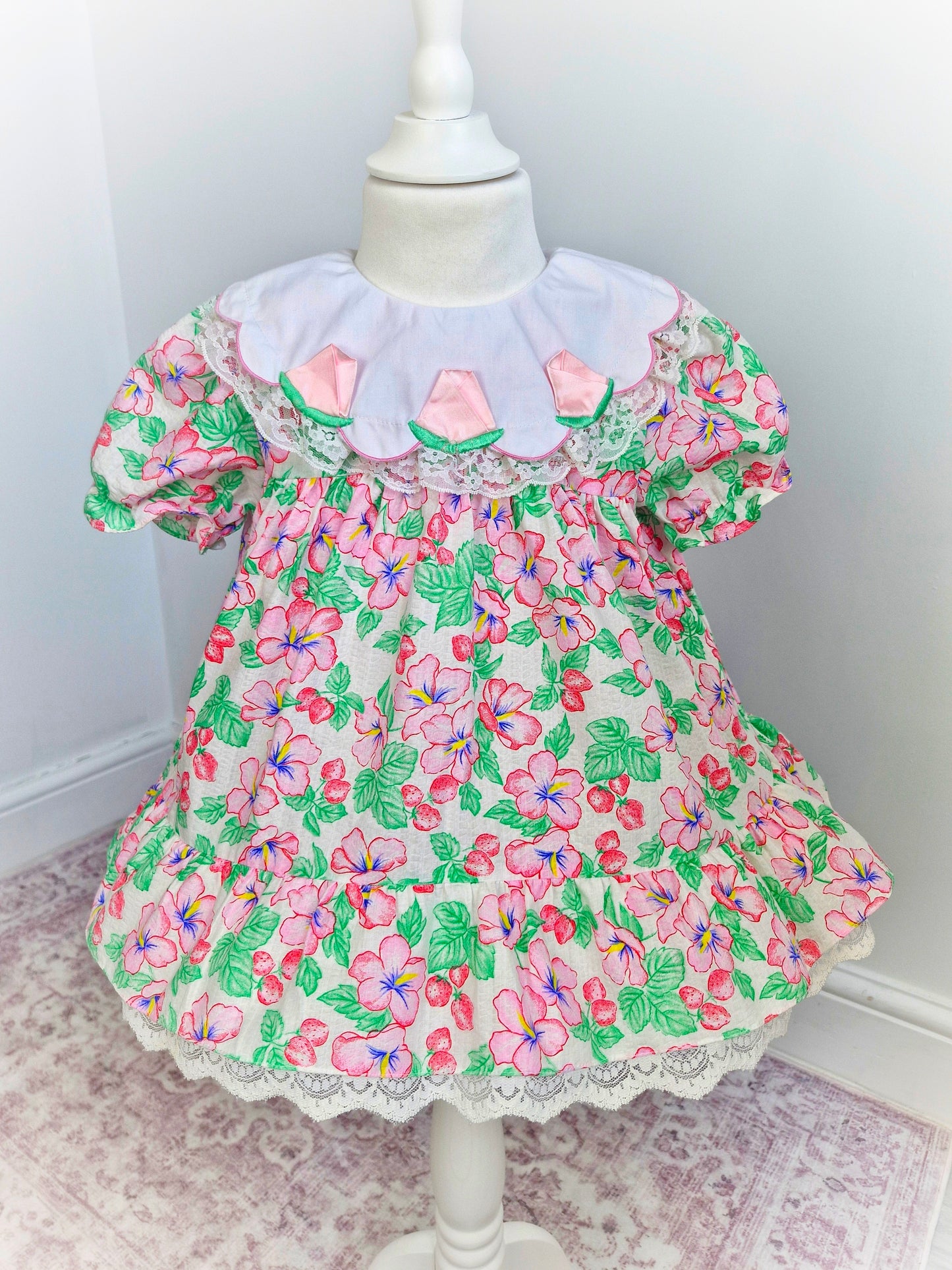 2 years. Strawberry and floral dress with white bib and roses. Lace detail on bib and hem