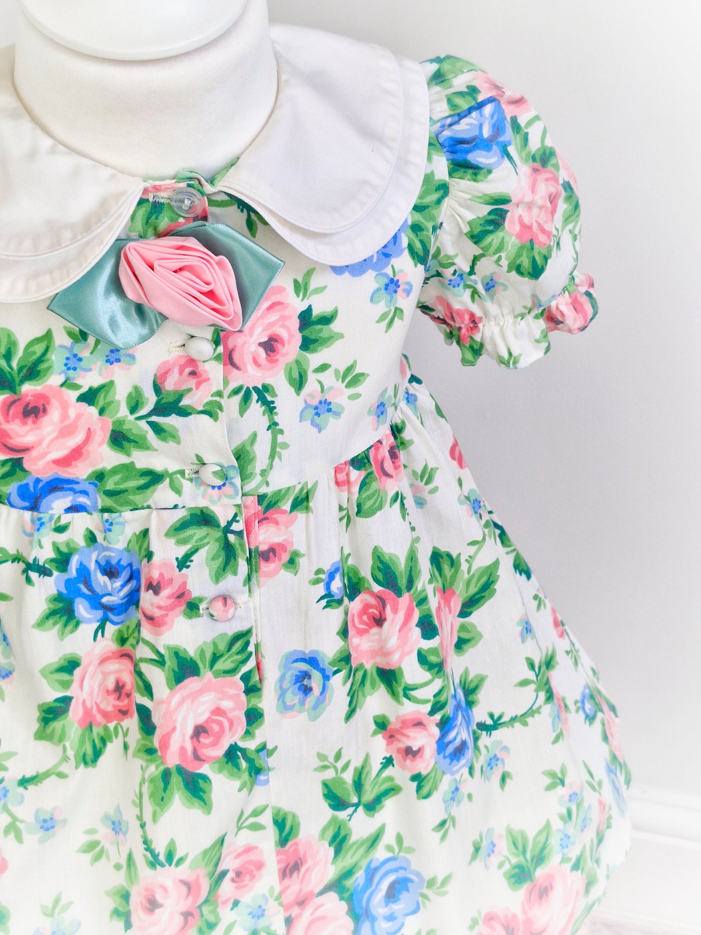 3 years. Blue and pink floral dress with double white collar and rose centre