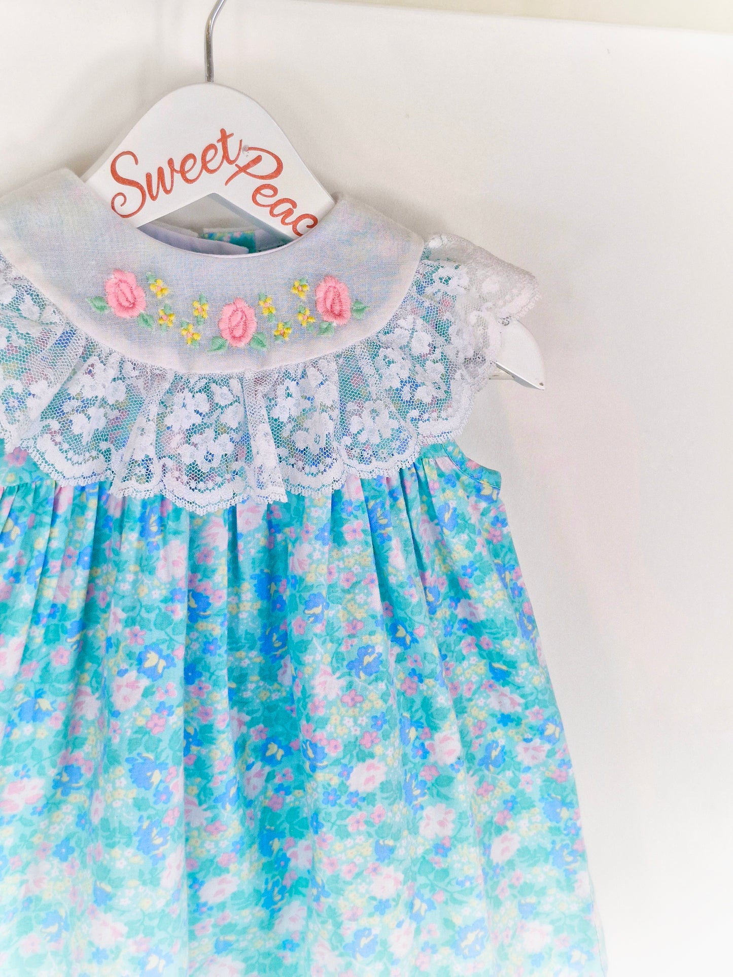12 months. Blue floral sleeveless Alyssa vintage dress with embroidered flowers and lace on bib