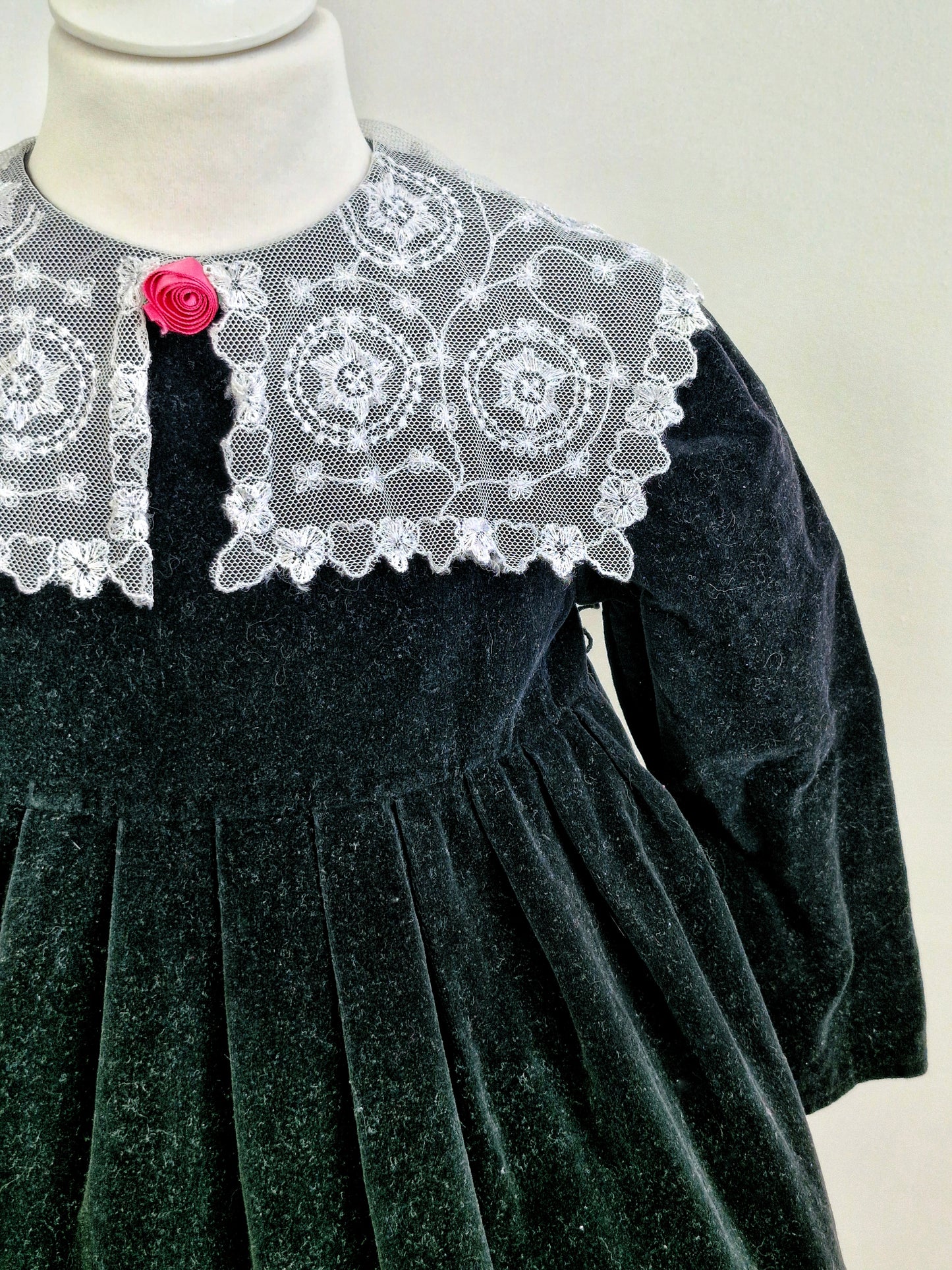 3-4 years. Black velvet vintage dress with white lace hem & collar and pink flower centre.