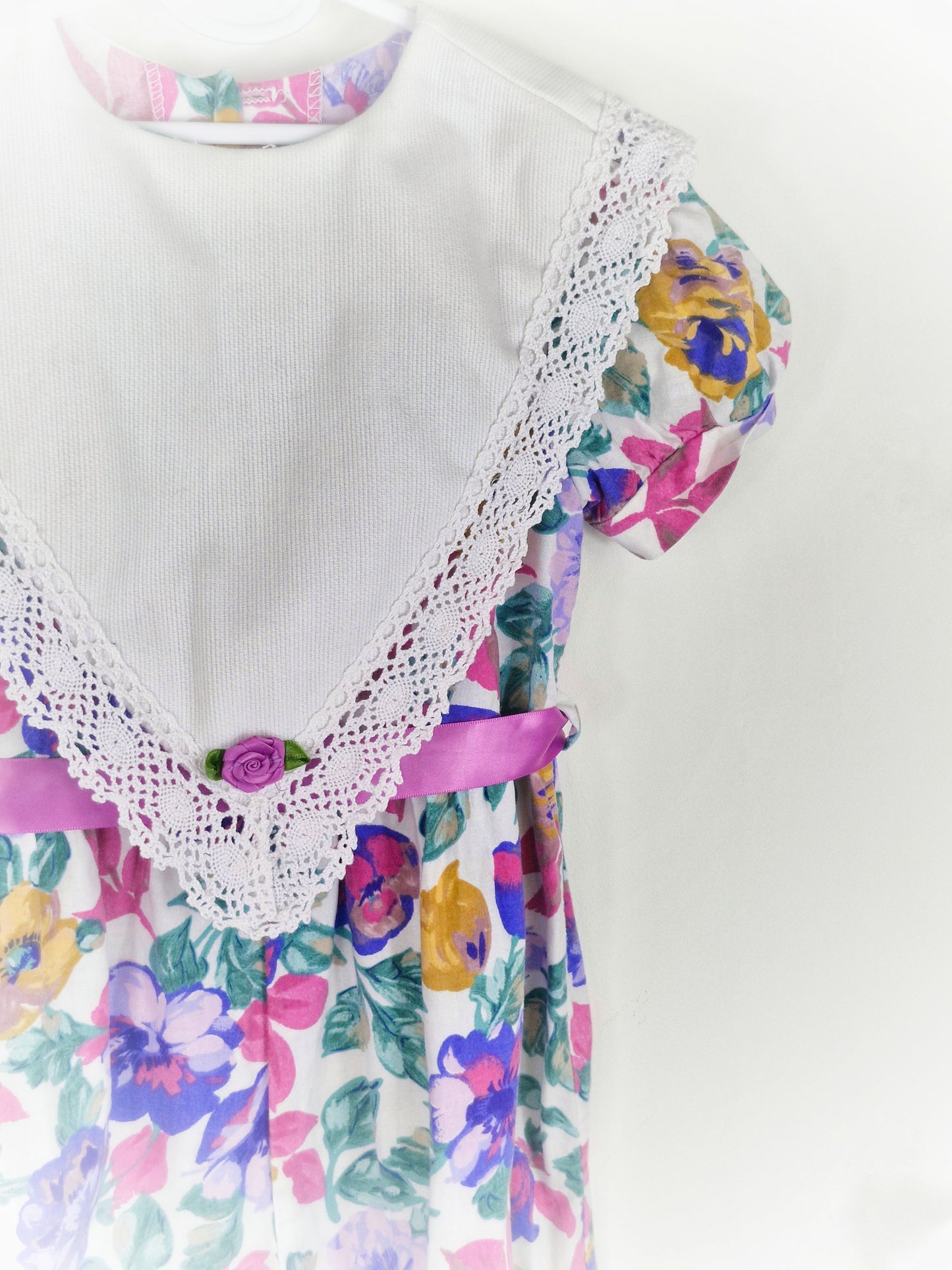 2-3 years. Purple floral romper with large white bib