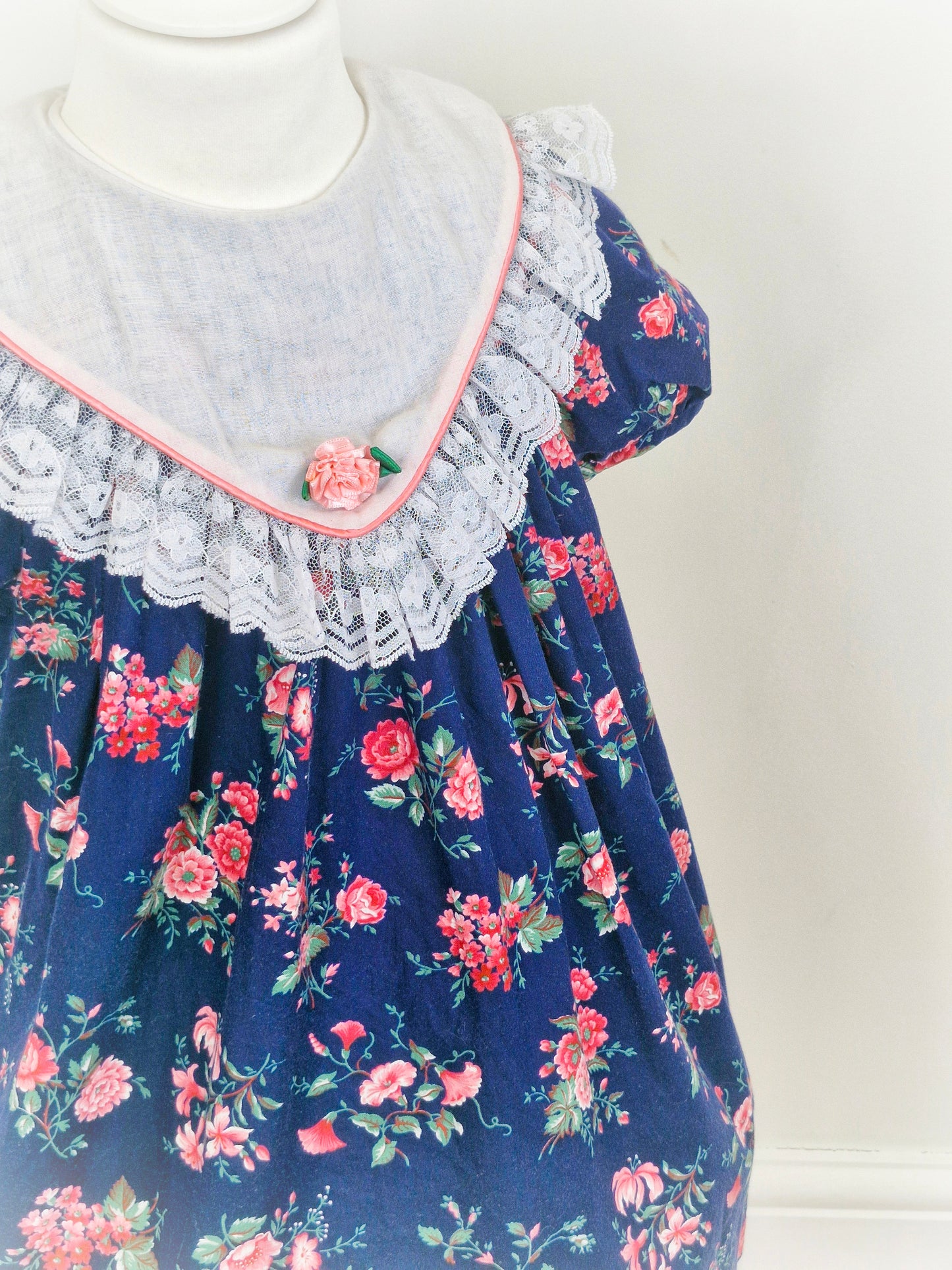 5 years. Navy vintage Rare Editions with pink floral print and large bib with lace hem