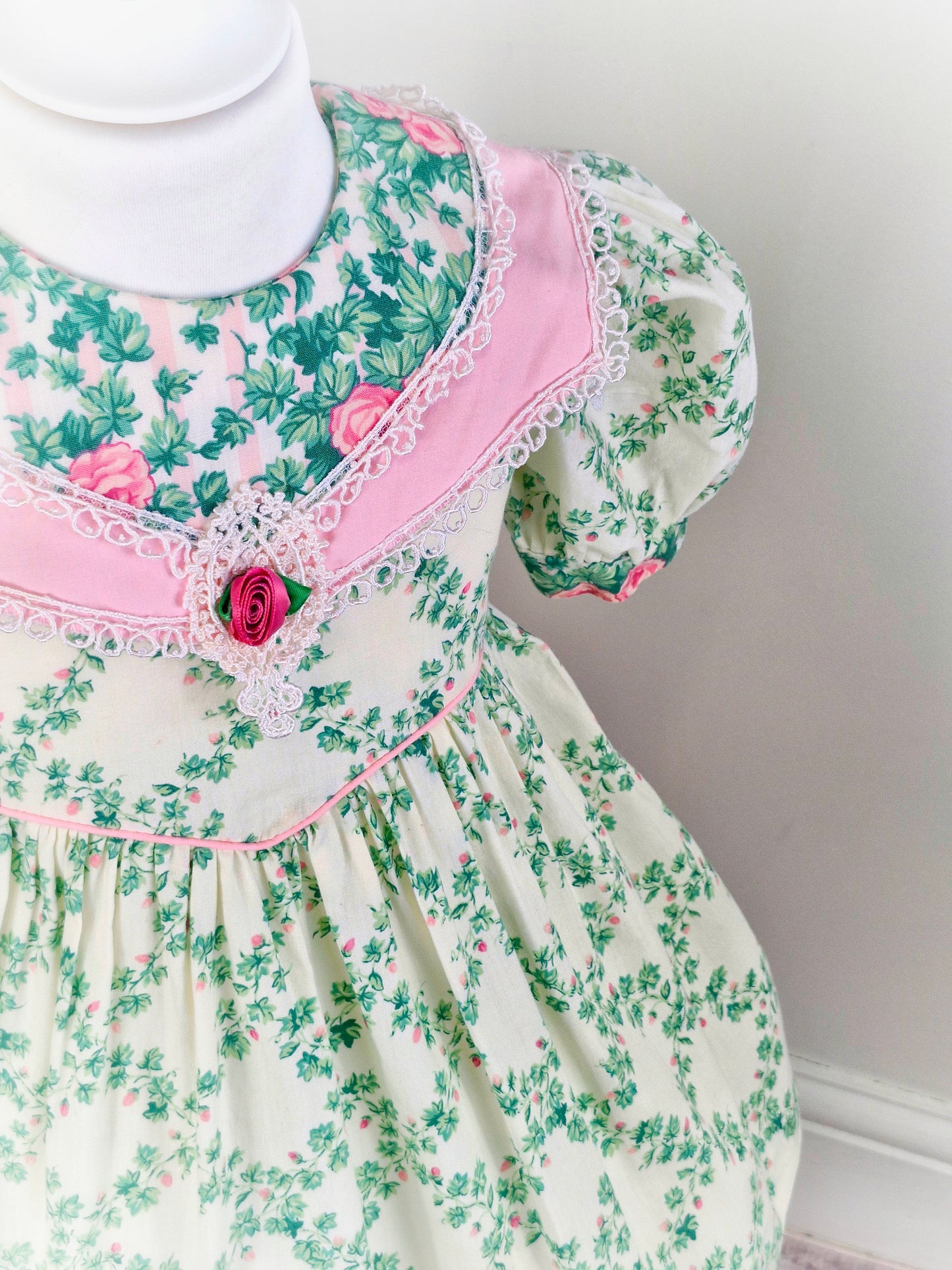 3 years. Vintage Carters dress with puffed sleeves, pink detailing and large bib. Ivy and floral patterns
