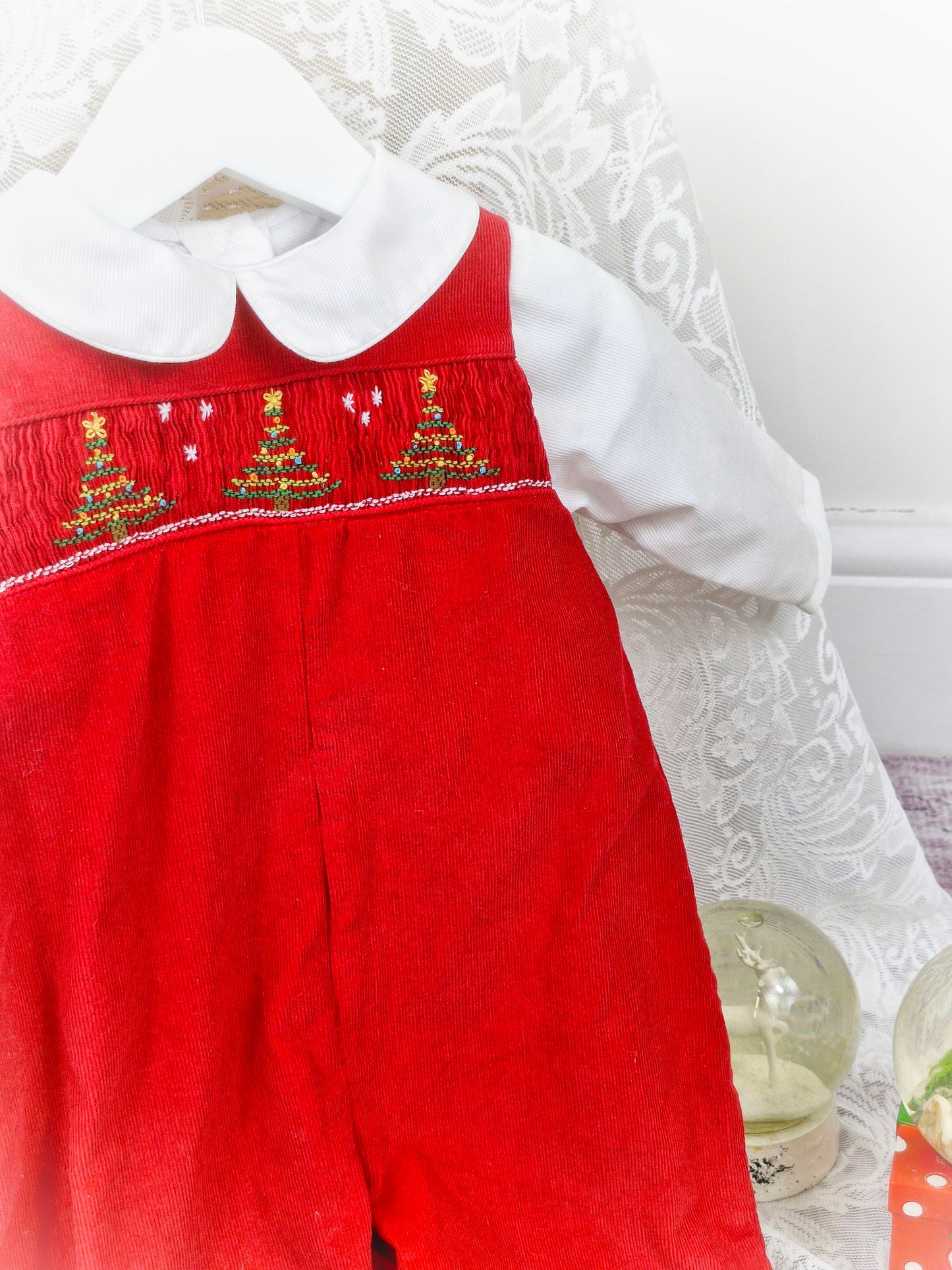 6-9 months. Two-piece set. Red corduroy dungarees with smocking and embroidered Christmas trees. Includes white collared shirt.