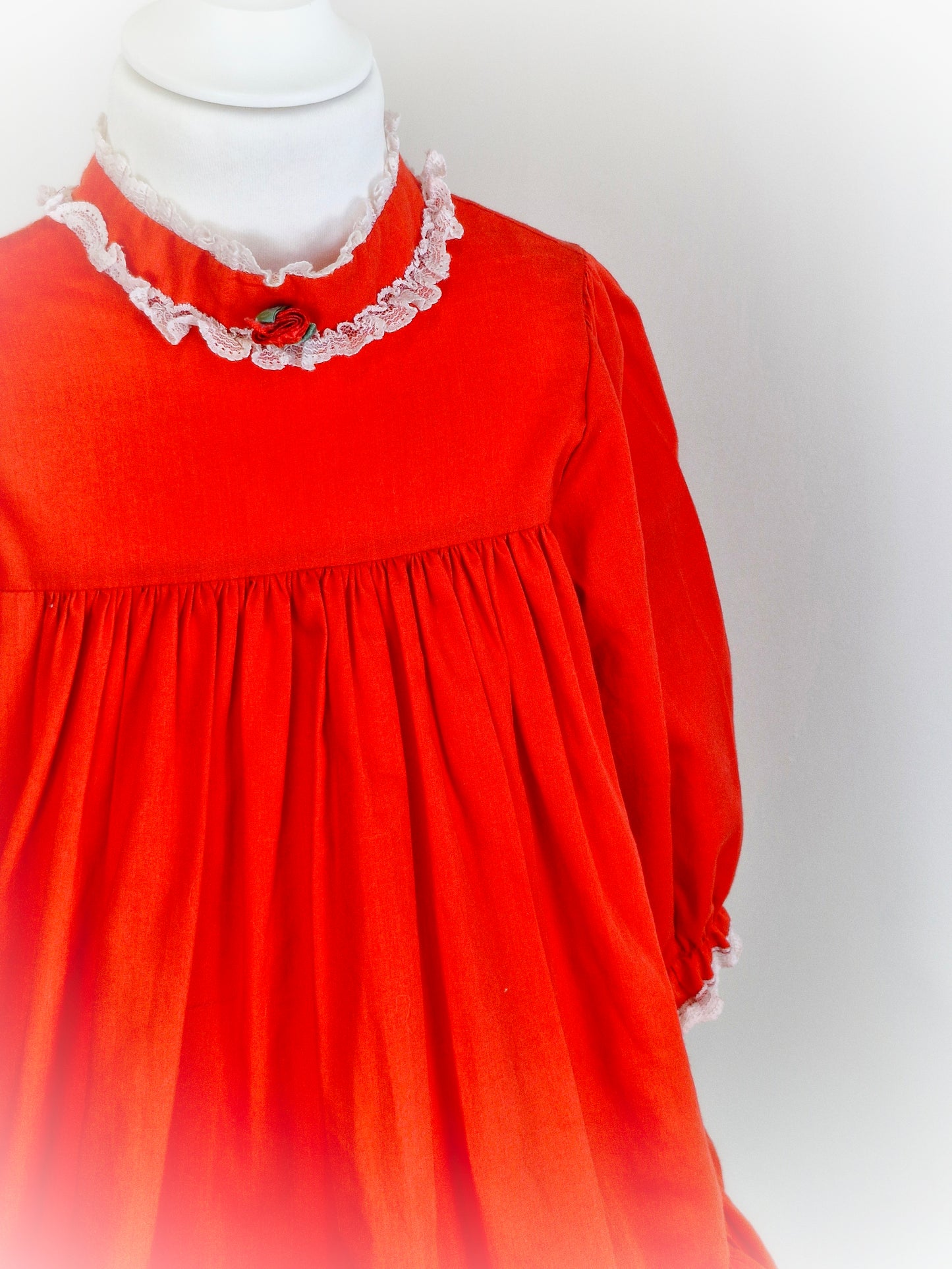 5 years. Red vintage Bryan with high neck and long sleeves. Lace and rosette detailing