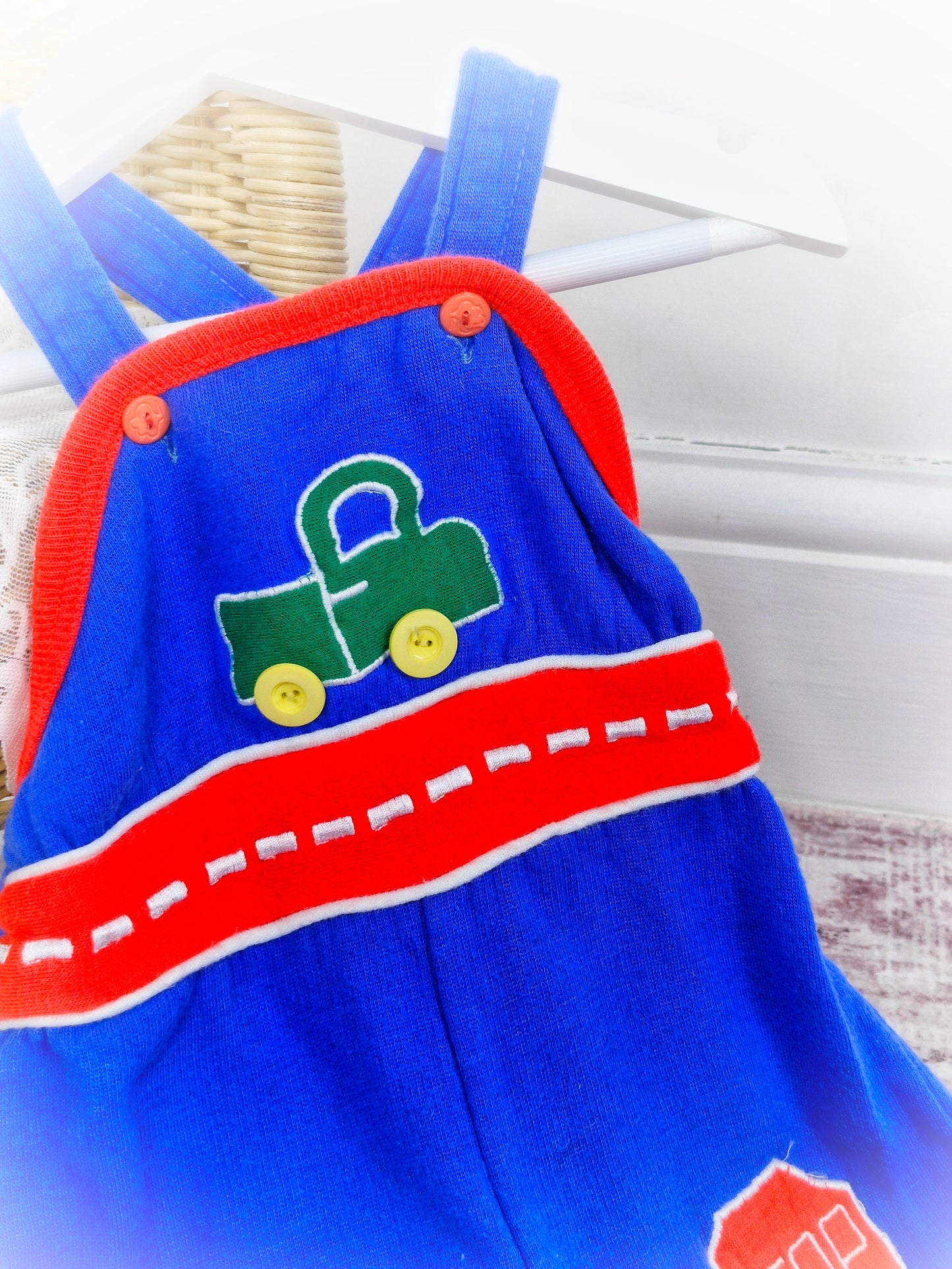 6 months. Blue dungarees with green car and red details