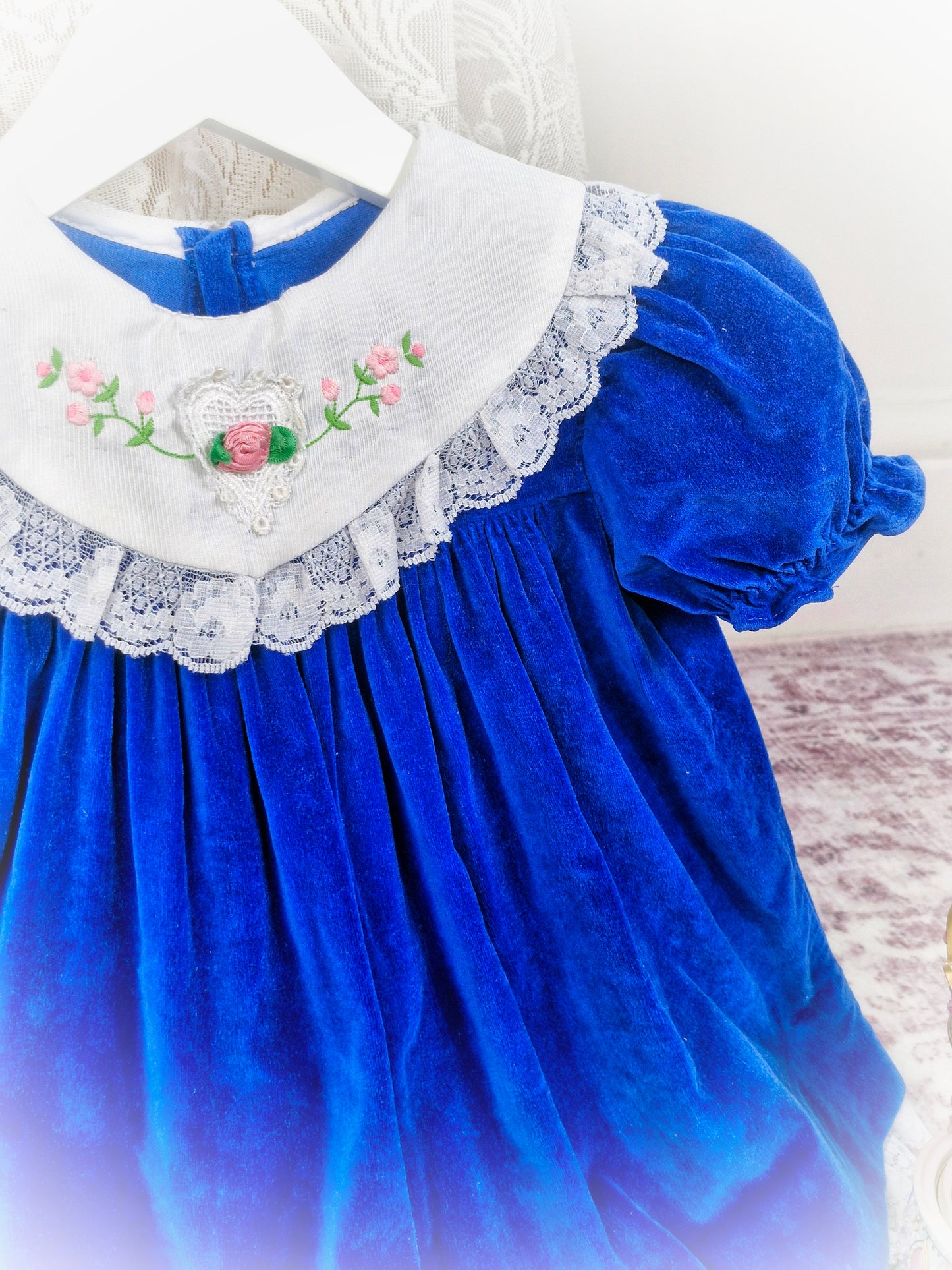 2 years. Royal blue, vintage velvet dress with puff sleeves, white bib and white lace trim. Embroidered flowers