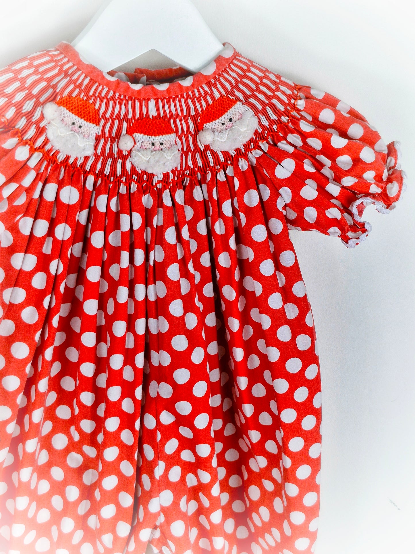 6-12 months. Red and white polka dot smock romper with embroidered santas