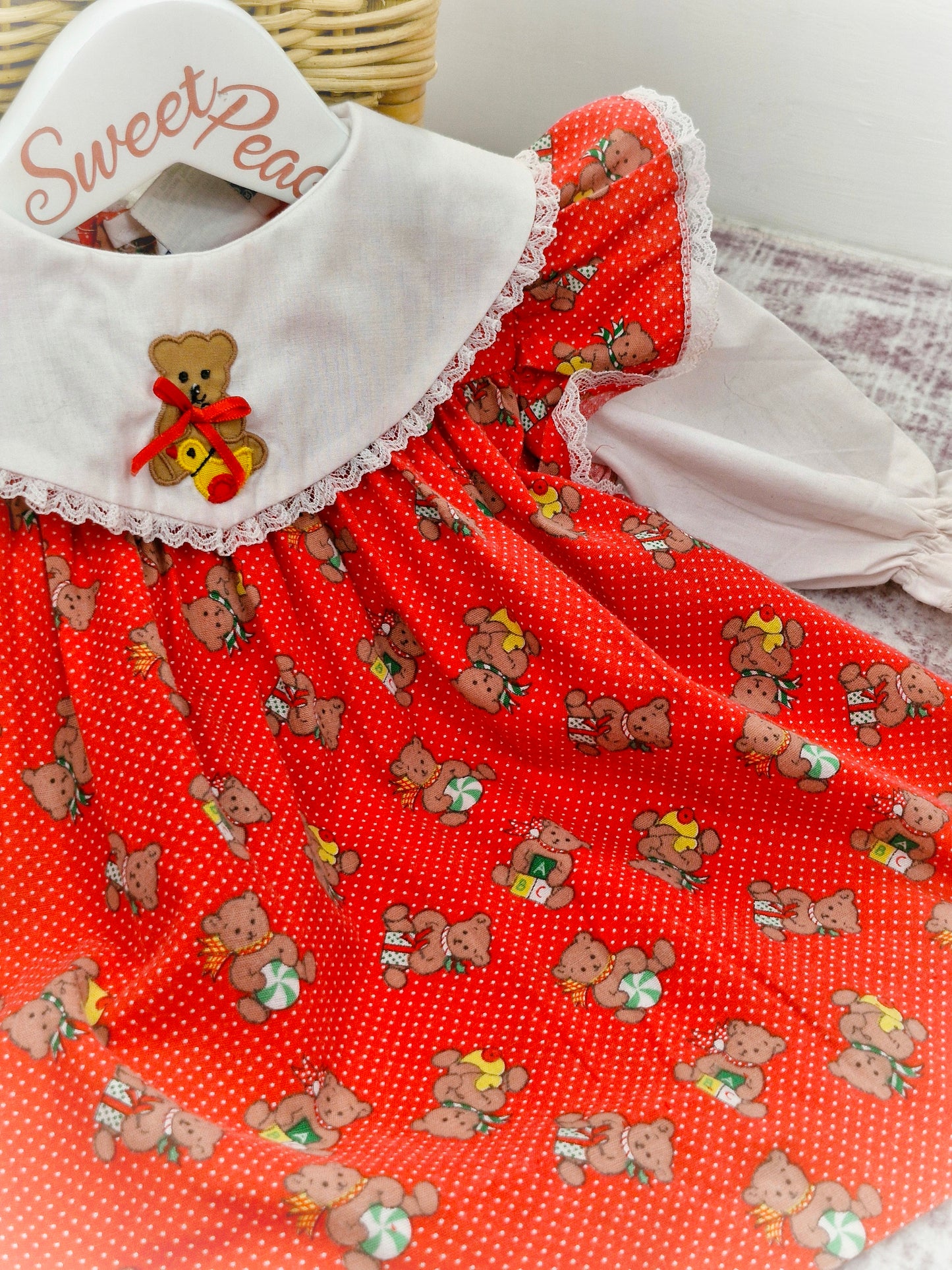 9-12 months. Red polka dot vintage dress from Nannette with white sleeves and bib, christmas teddy print and and flutter shoulders