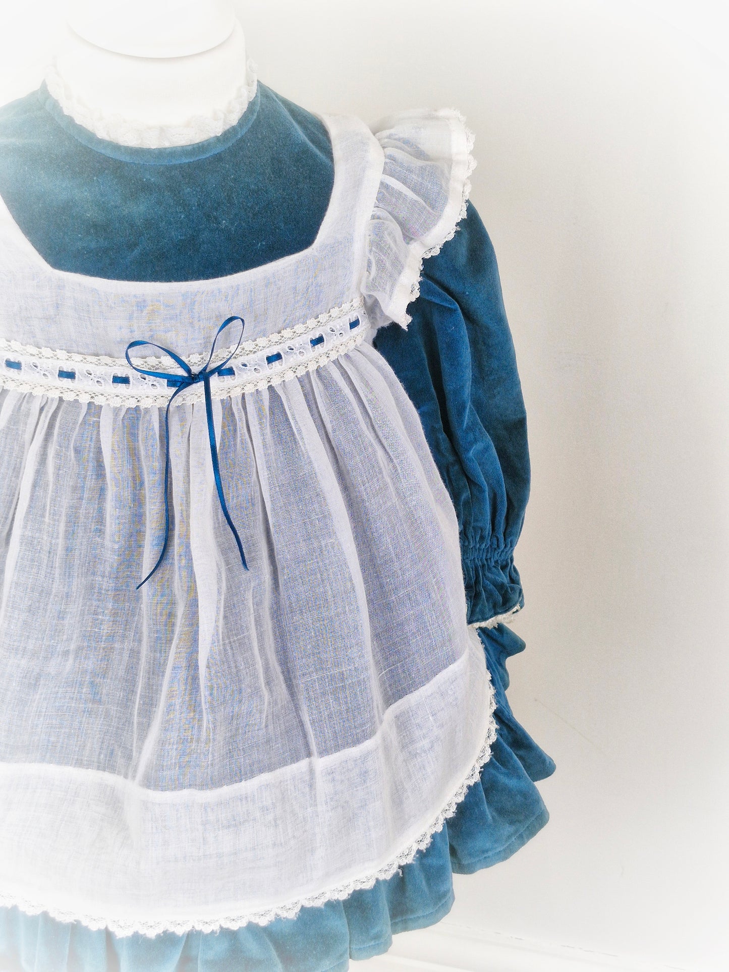 2 years. Vintage teal velvet dress with white apron, frill shoulders and ribbon details