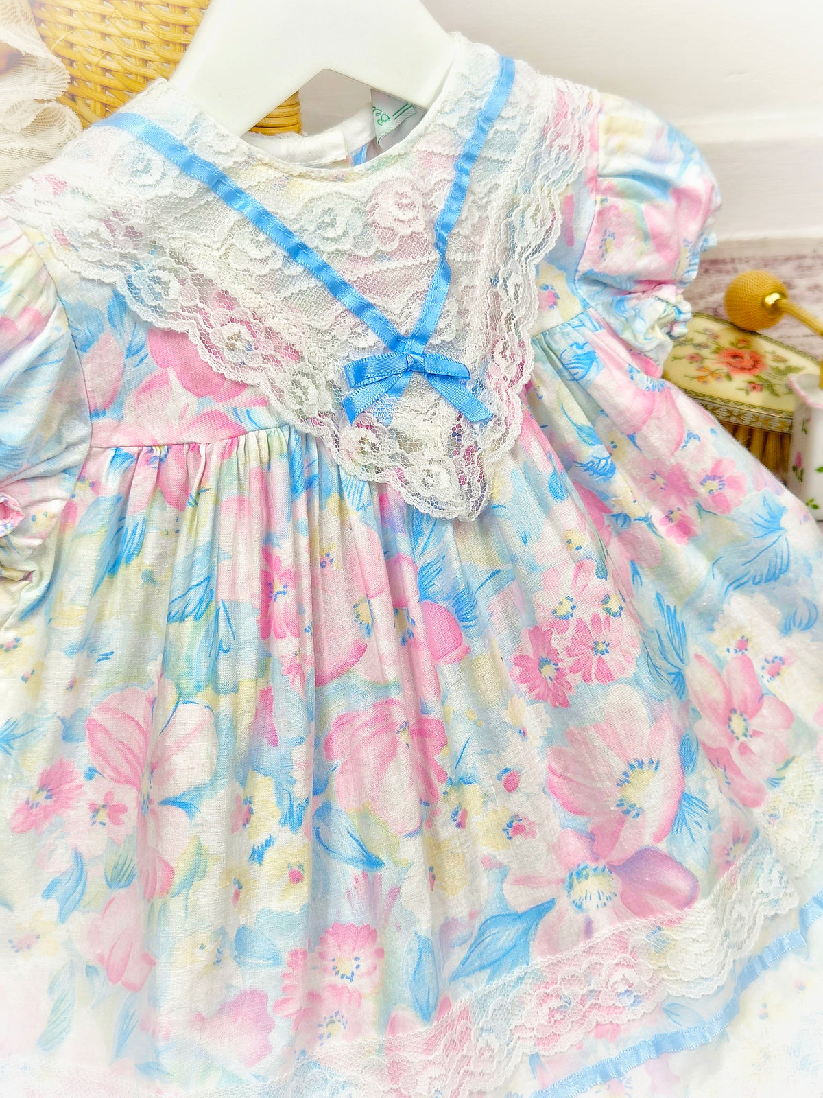 12-18 months. Pastel coloured floral vintage dress with lace bib and blue satin ribbon