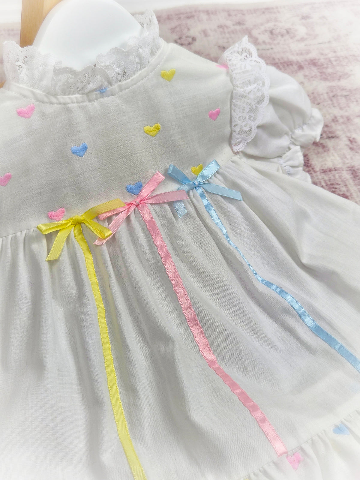 9-12 months. White vintage dress with pink, blue and lemon embroidered hearts and satin ribbons and bows