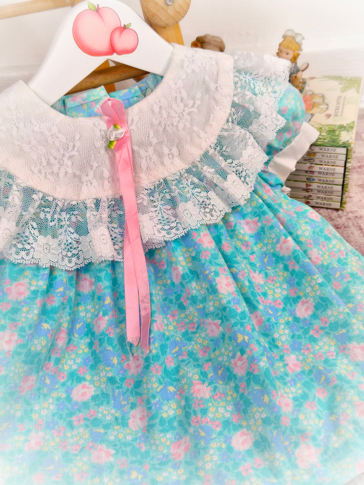 12 months. Turquoise vintage dress from Evy with pink floral print, white lace bib and hem and pink satin ribbon