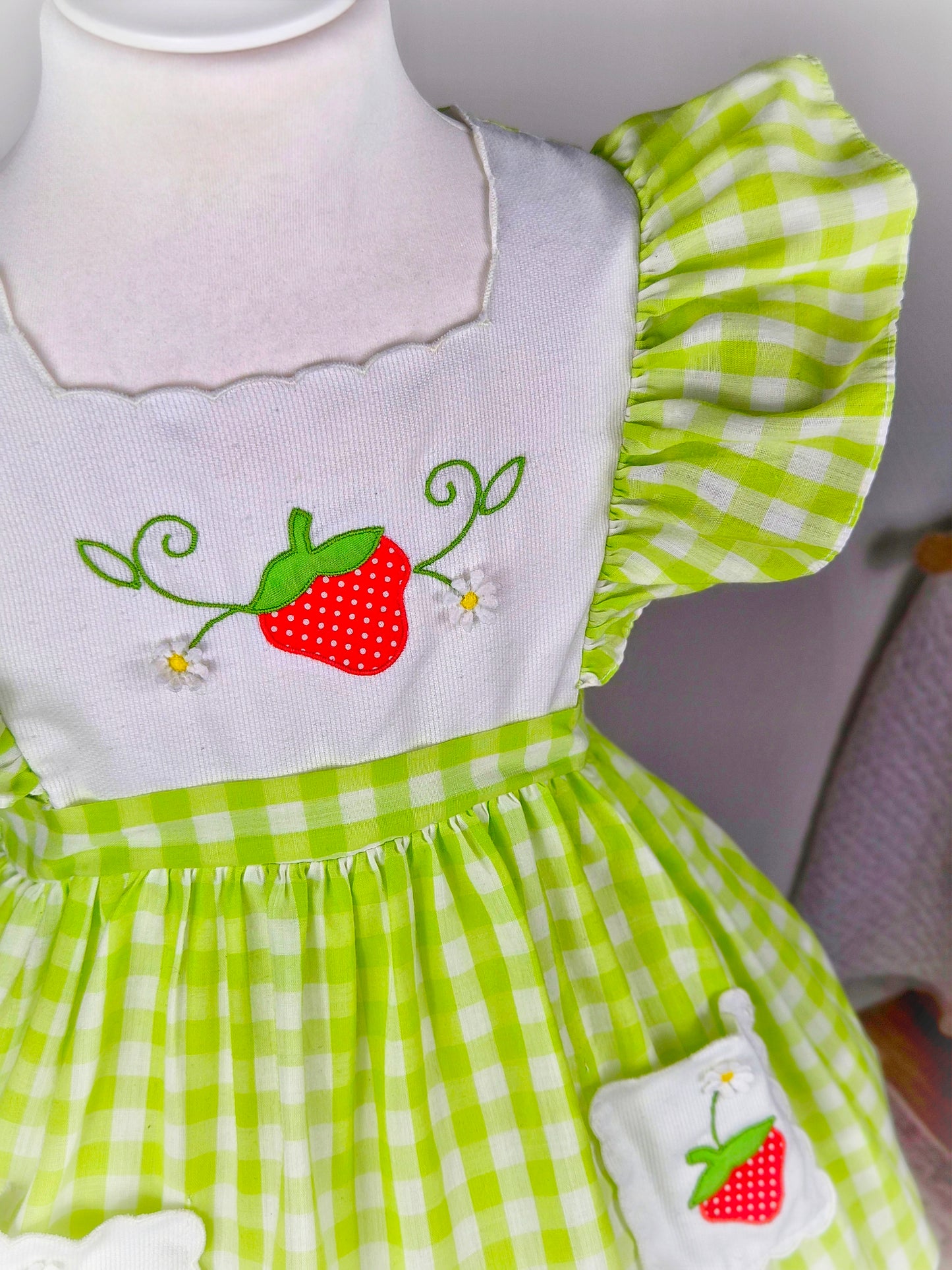2-3 years. Green and white vintage gingham dress with flutter sleeves, white bib and pockets embroidered with strawberries from Nannette