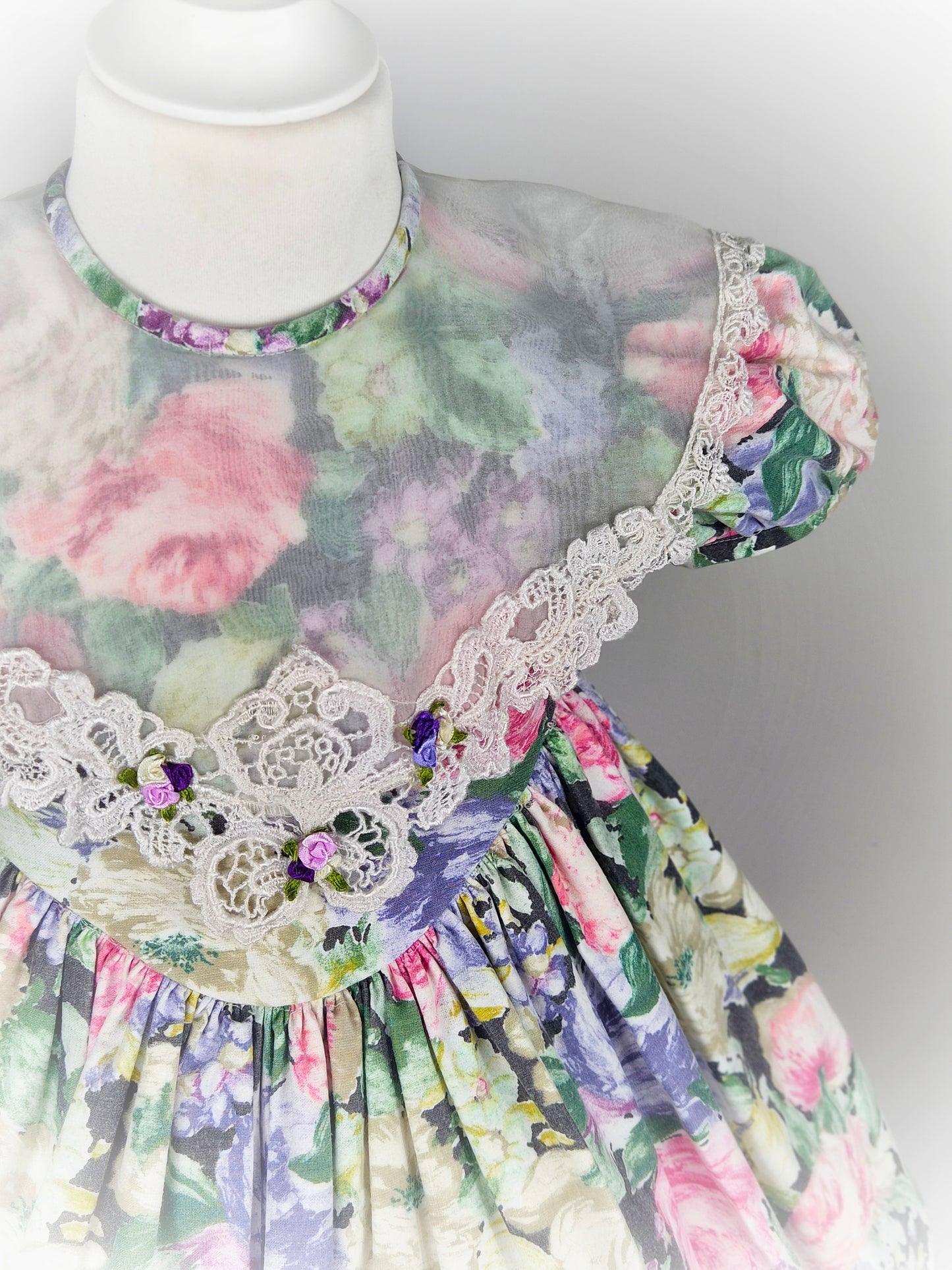 3 years. Vintage floral dress with puff sleeves, large sheer bib trimmed with lace and rosettes
