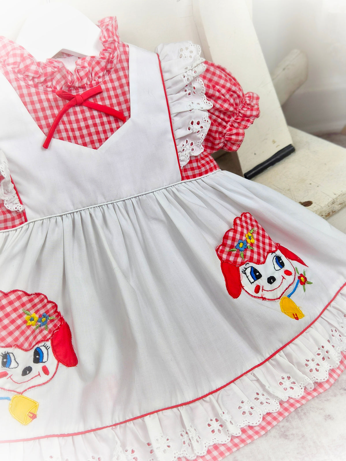 9-12 months. Red and white gingham dress with white mock apron, eyelet details and little sheep appliques