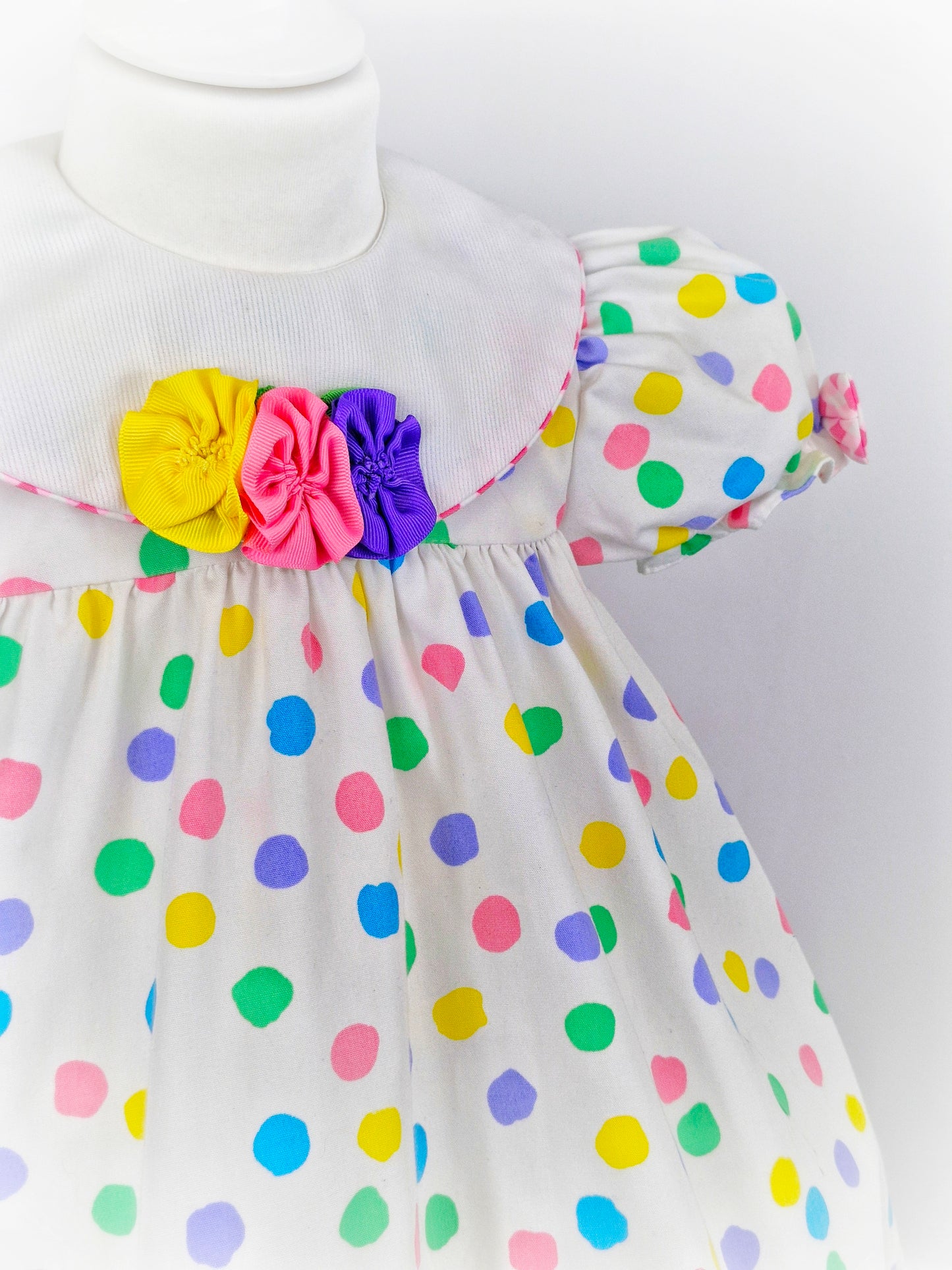 2-3 years. White dress with bright coloured spots and detailed bib