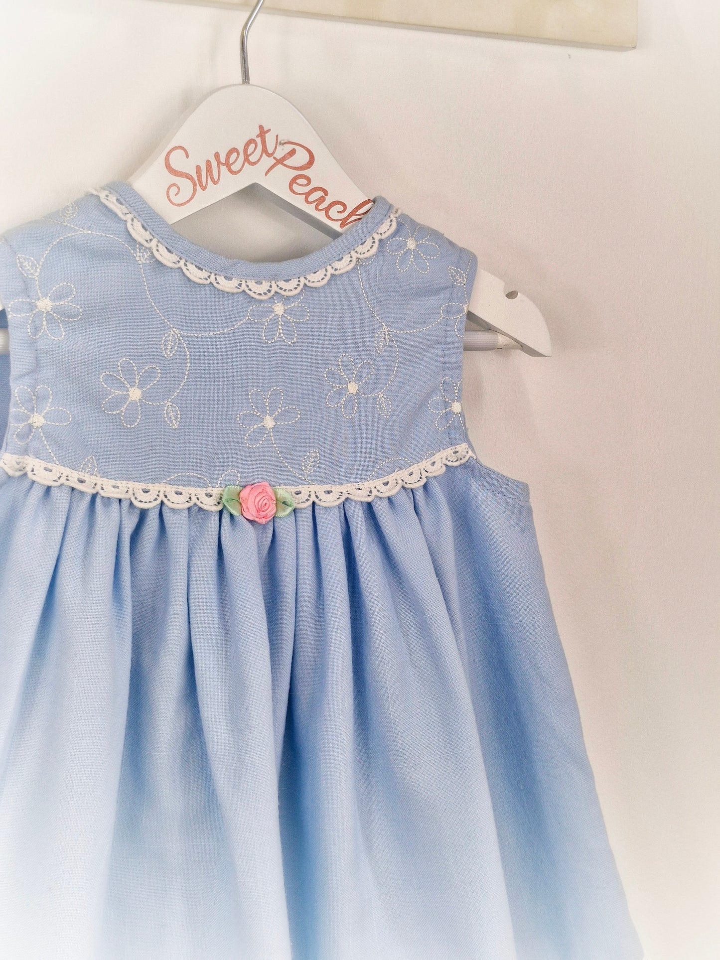 2 years. Blue sleeveless dress with white details and pink rosette