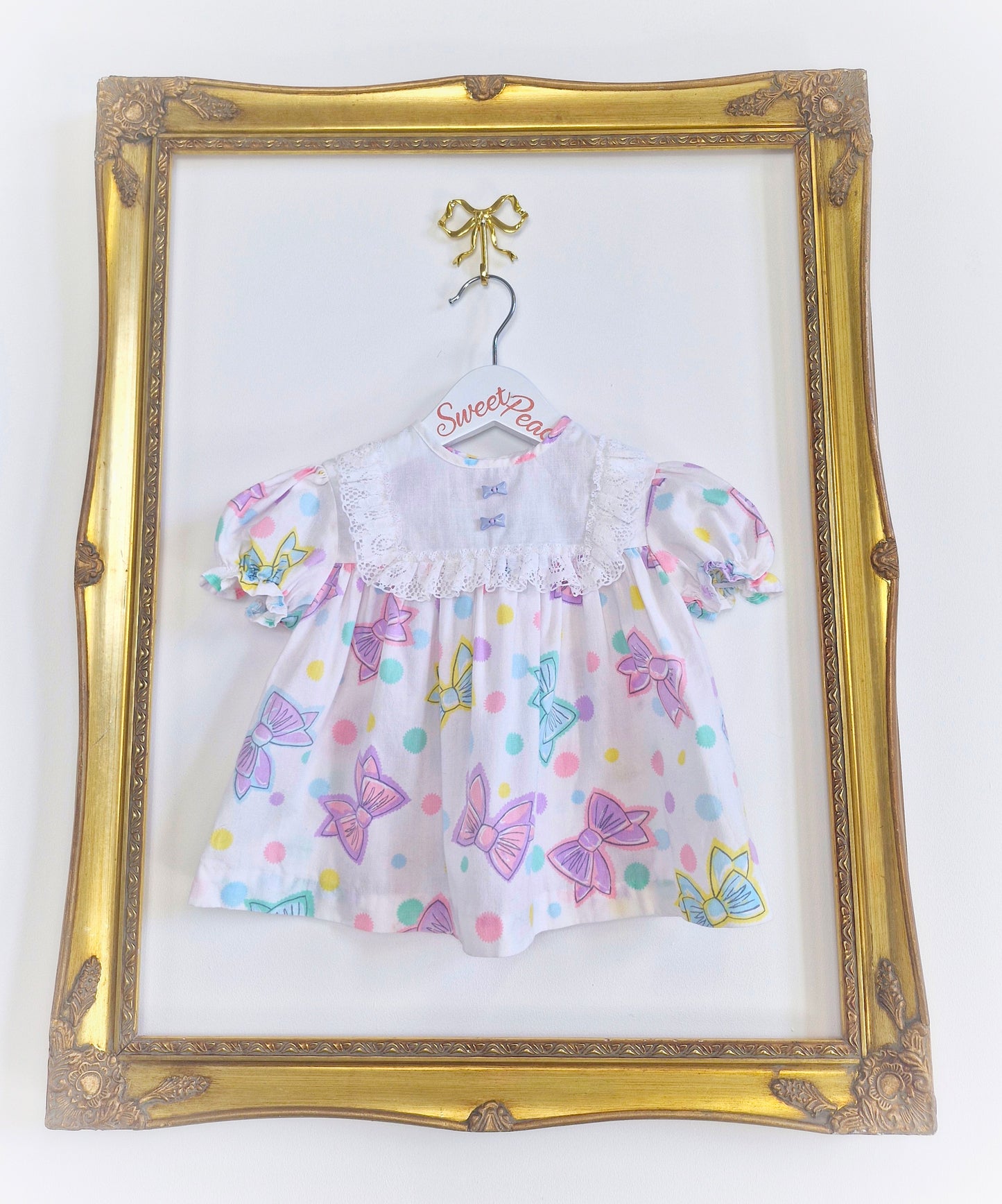 6-9 months. White 80s dress with bow print and buttons.