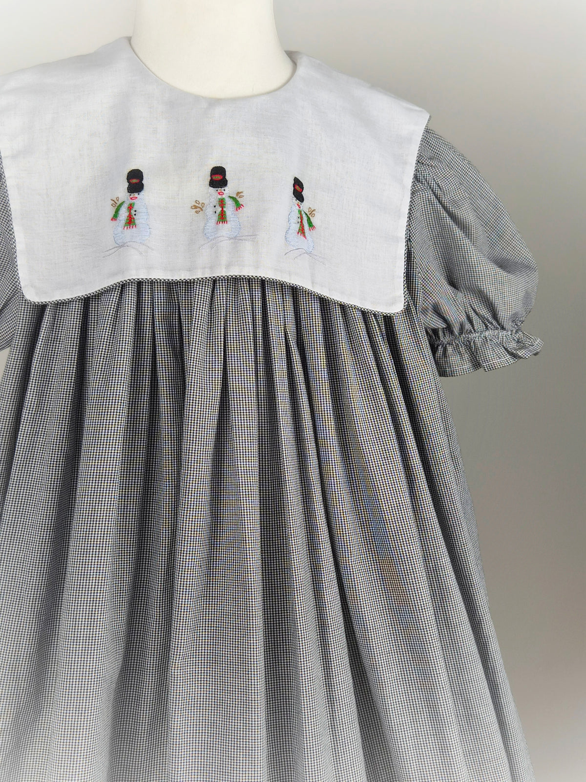 10 years. Black and white gingham, vintage handmade dress by Amanda Kertzembend with large white bib embroidered with snowmen
