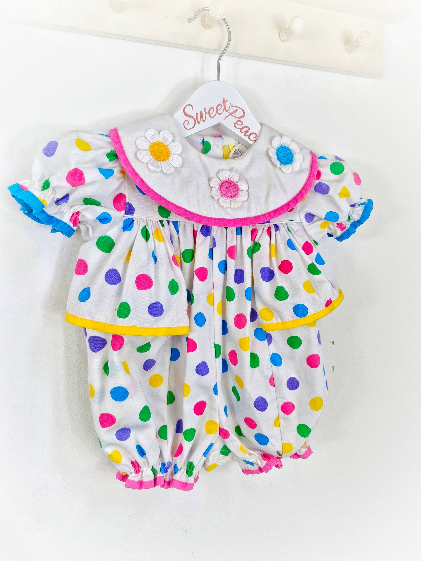 9-12 months. White romper with bright coloured spots and flowered bib
