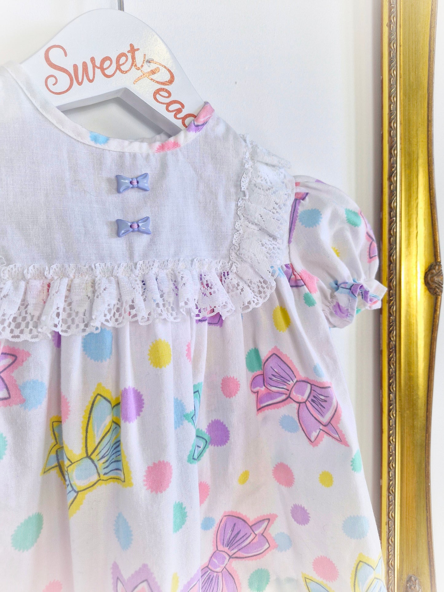 6-9 months. White 80s dress with bow print and buttons.
