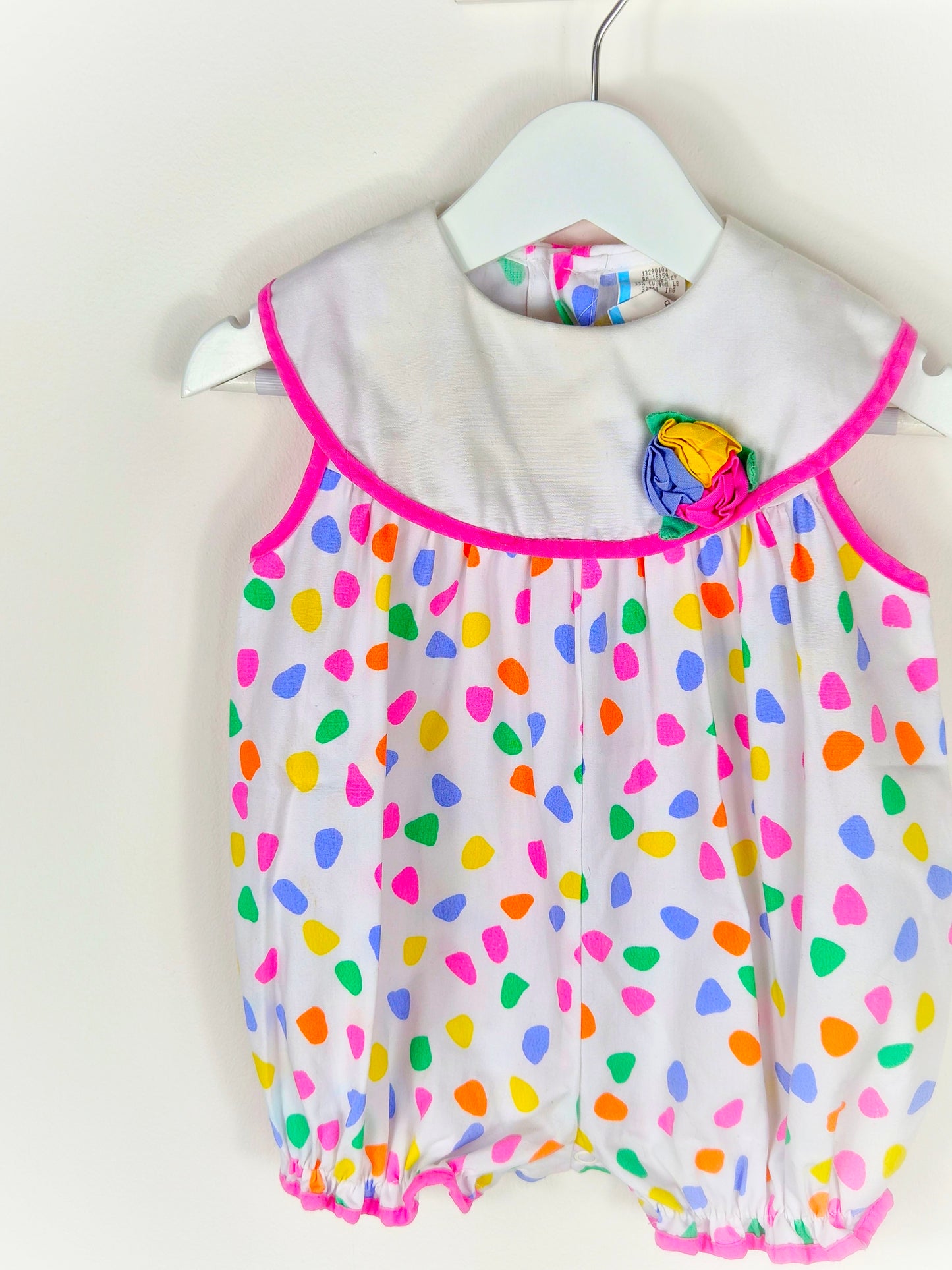 12 months. White vintage short, sleeveless romper with bright spots and flower on bib