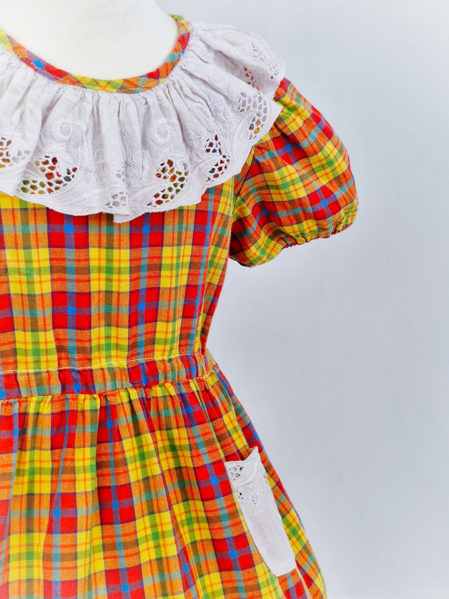 3 years. Checked dress, with white embroidered bib, pockets and hem. yellow orange blue
