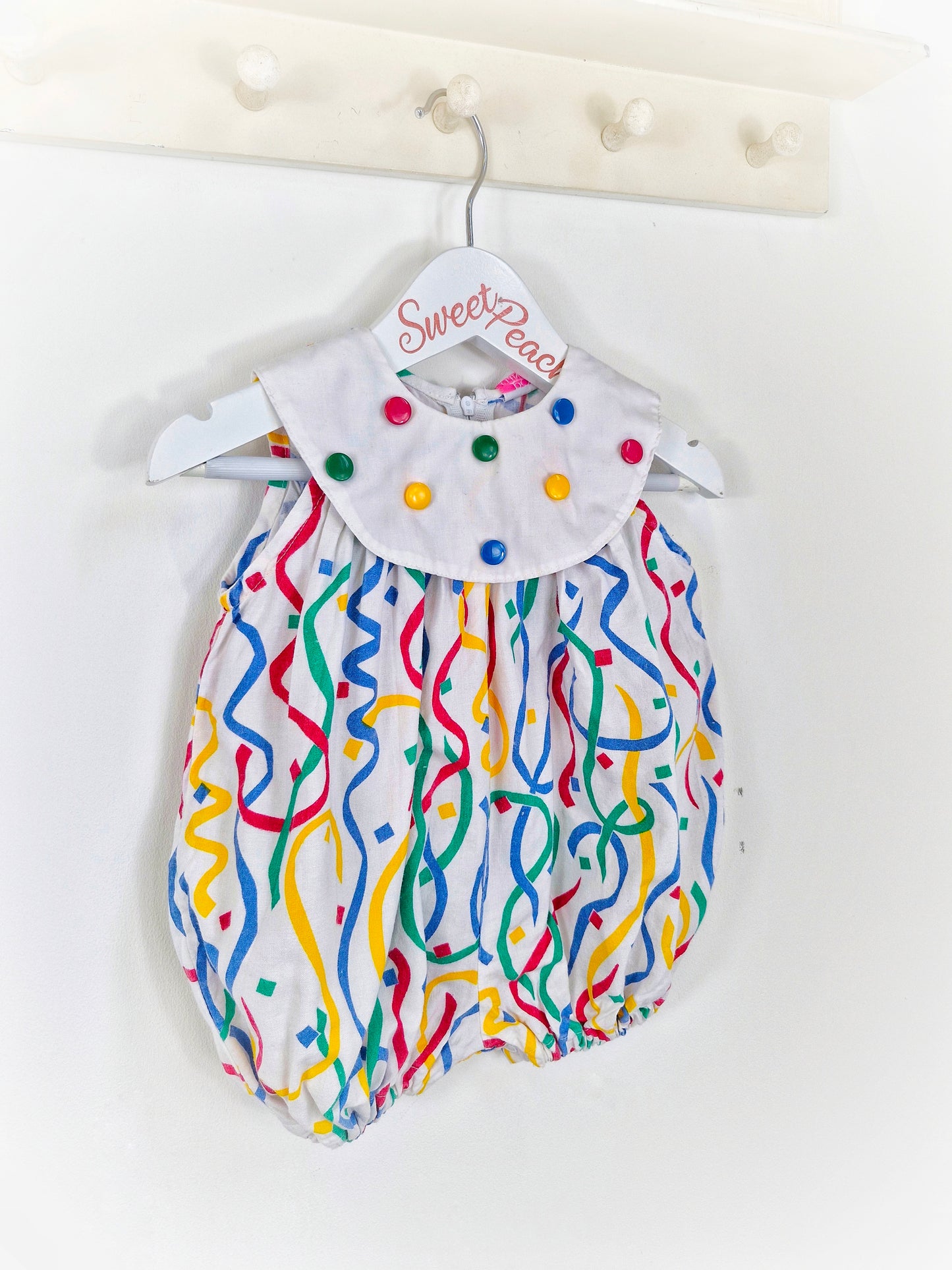 9 months. Polly Flinders romper with primary coloured buttons and print