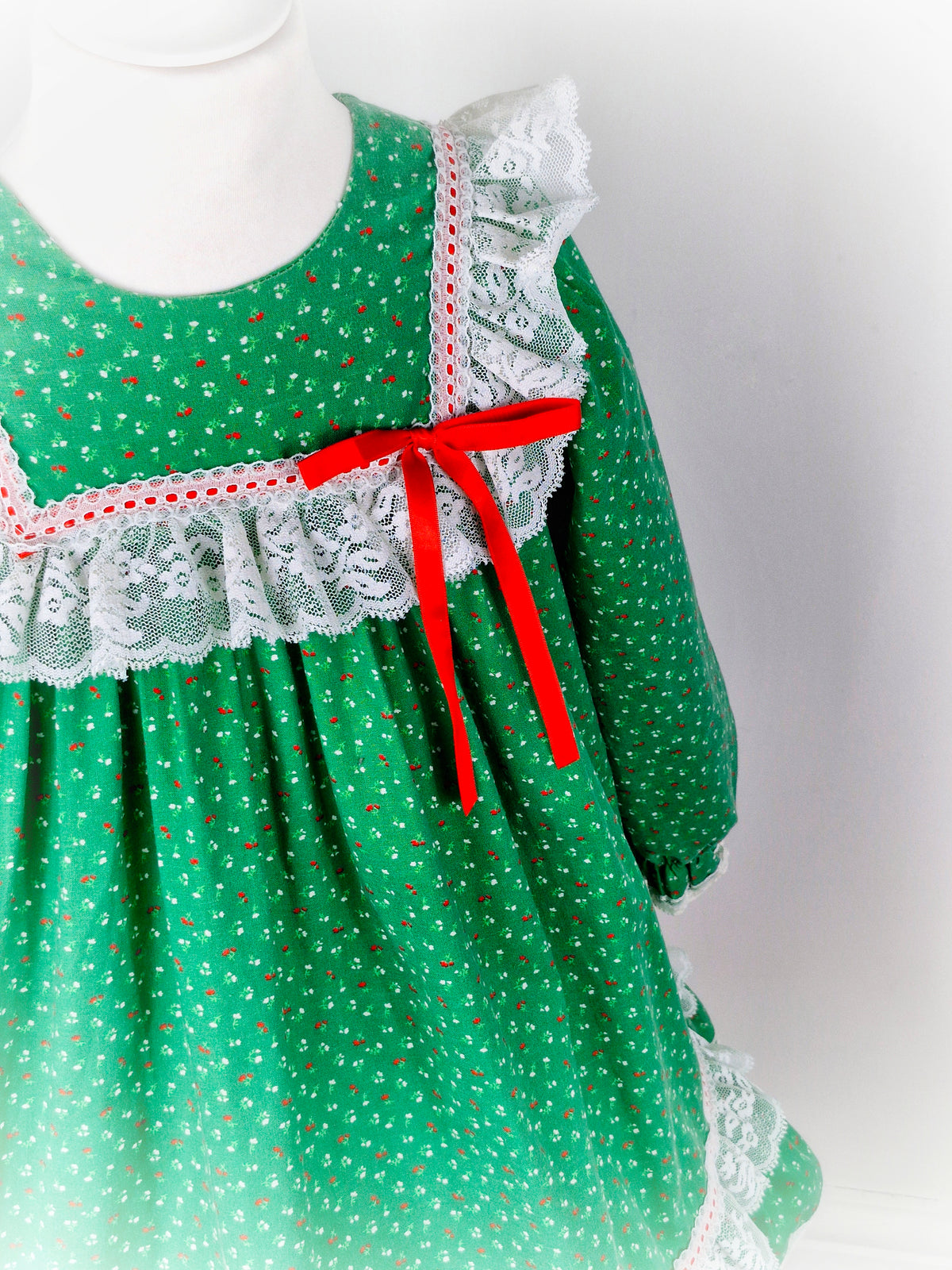 6 years. Green vintage Bryan with red and white floral print, white lace details and red ribbon