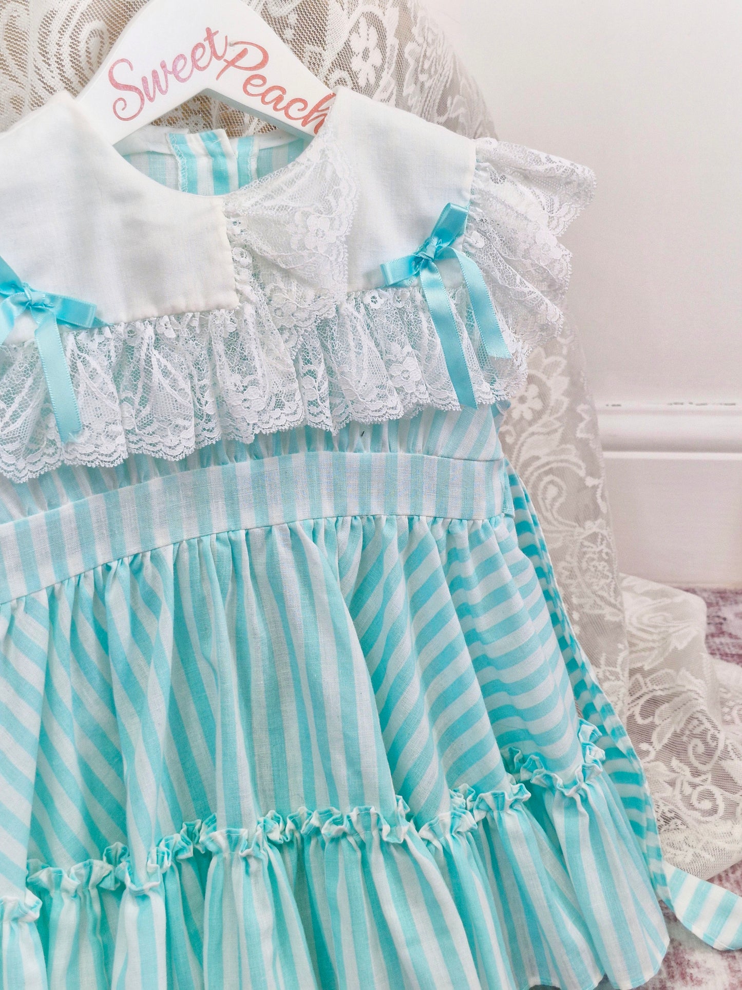 2 years. Mint and white sleeveless, striped dress with white bib, lace and bows
