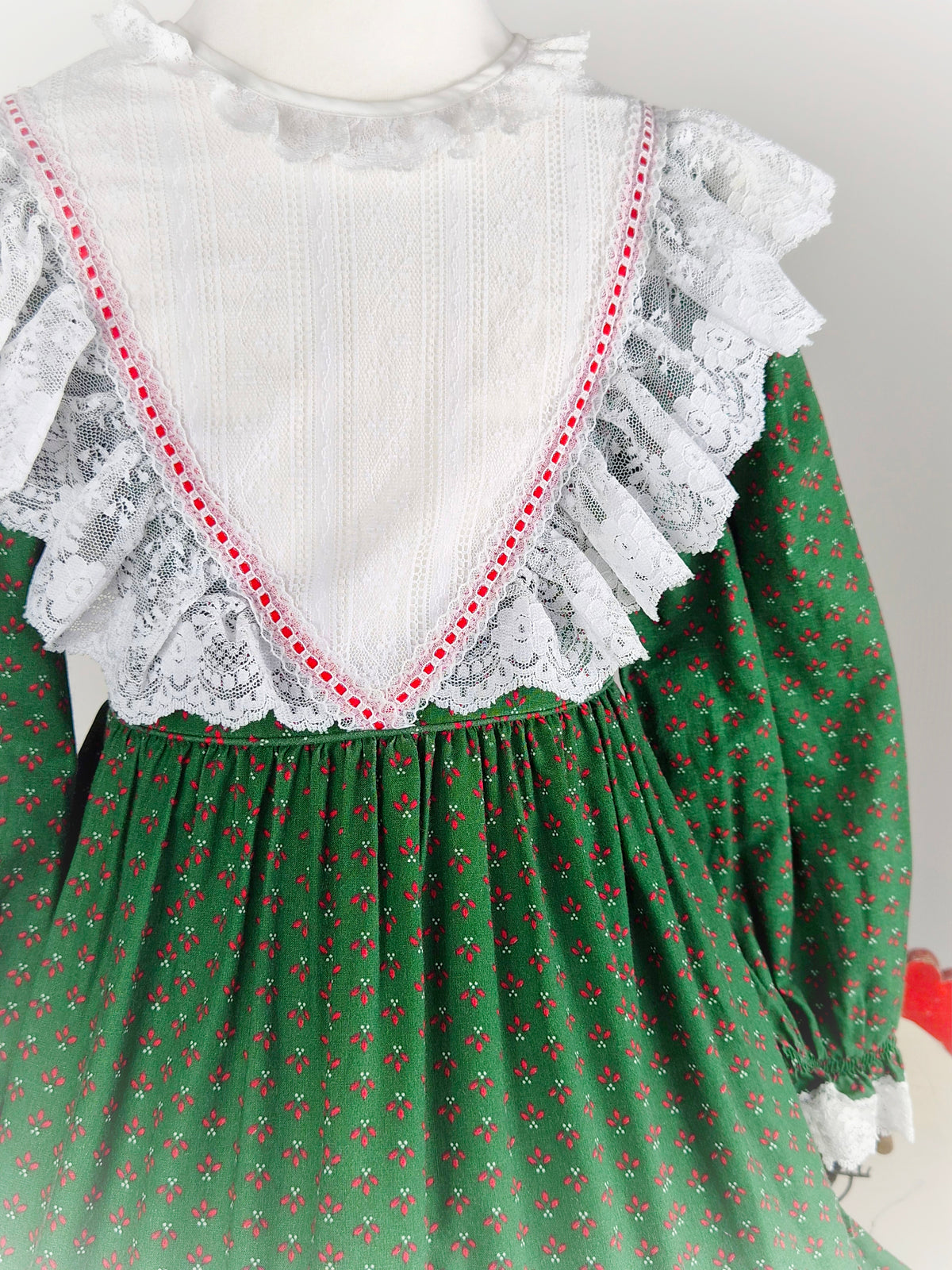 5-6 years. Forest green vintage Bryan prairie dress with red design and white frilly lace bib