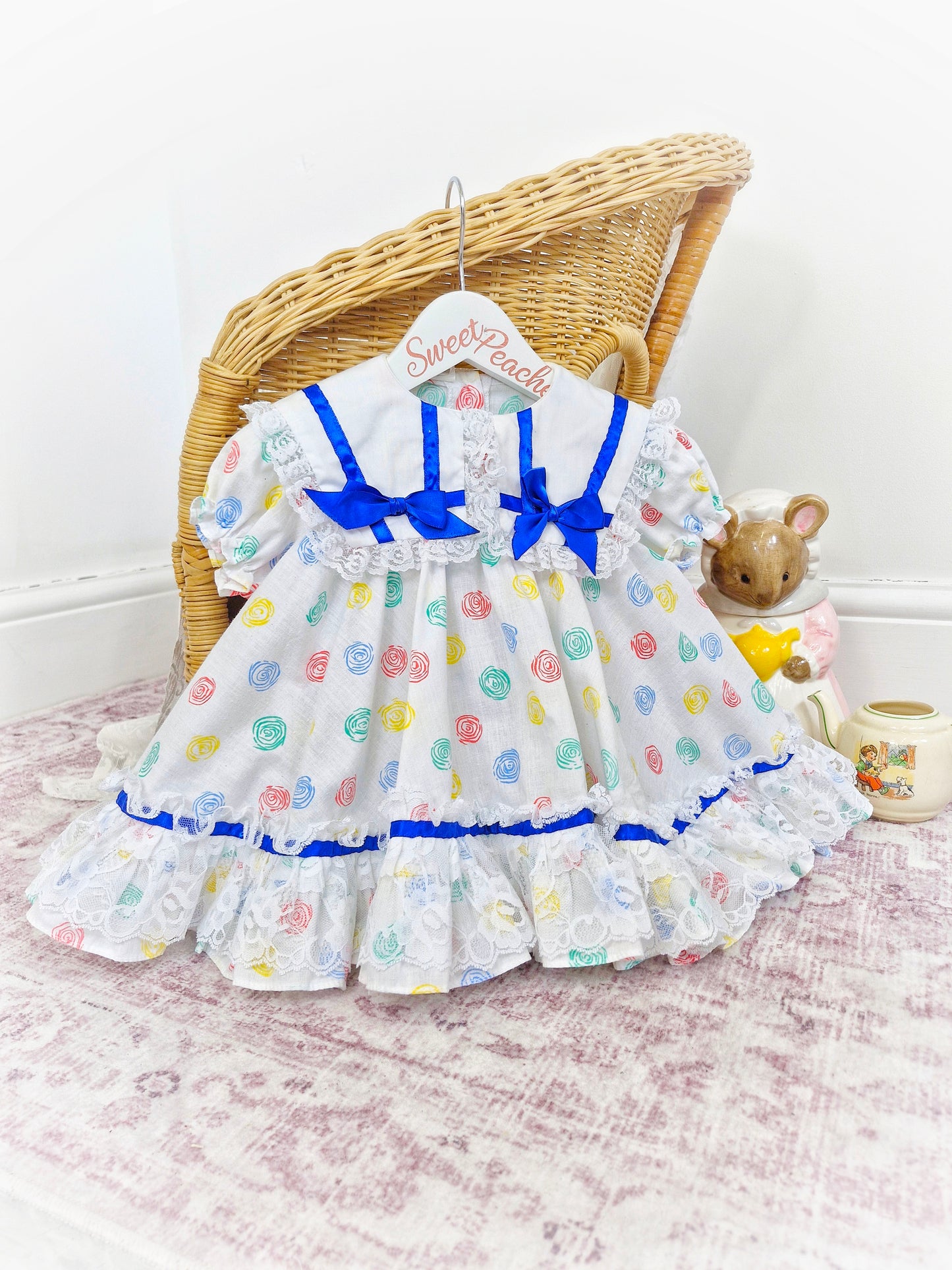 12-18 months. White Kotton Kandi dress with royal blue ribbon, lace and primary coloured prints