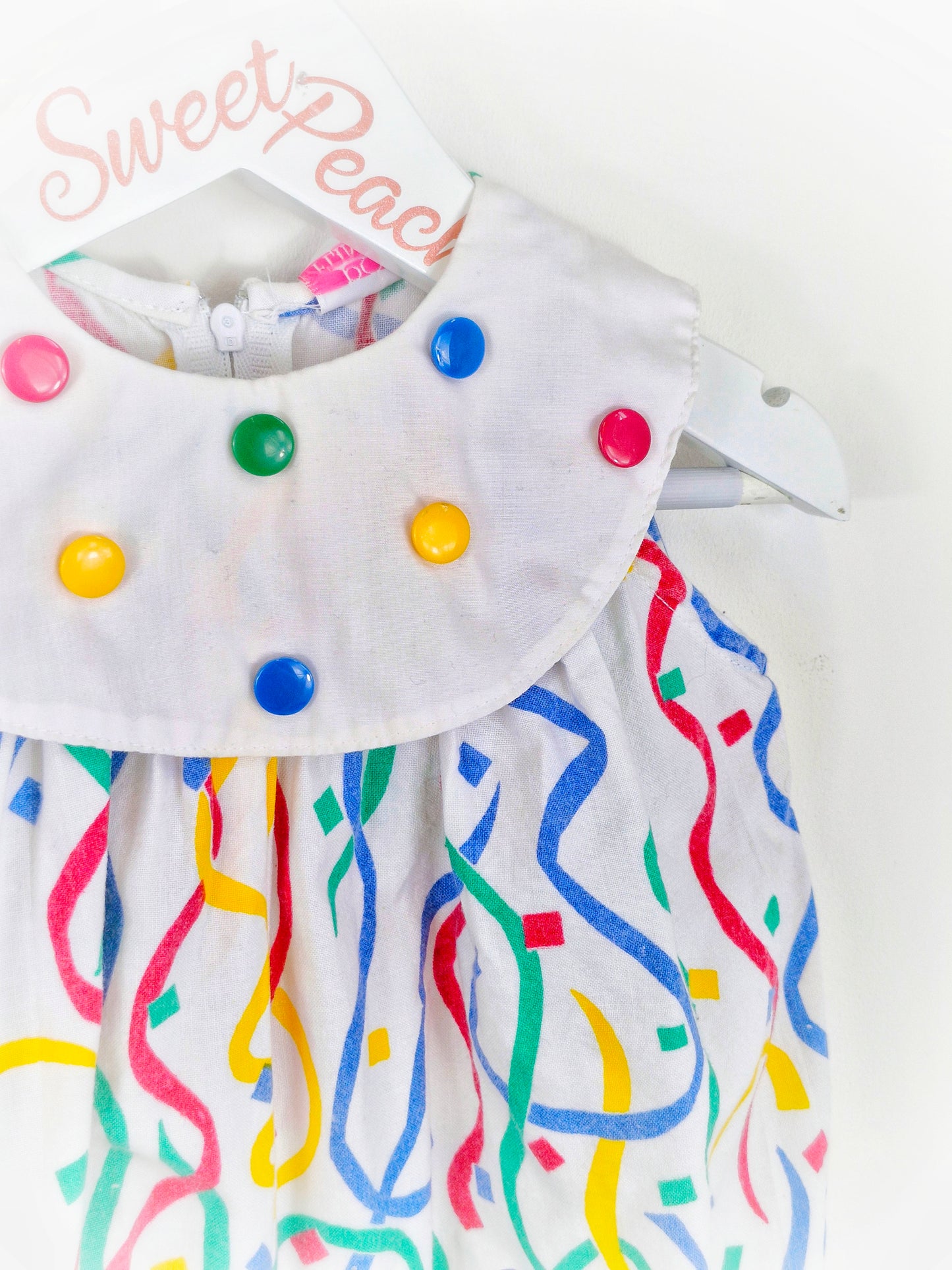 9 months. Polly Flinders romper with primary coloured buttons and print