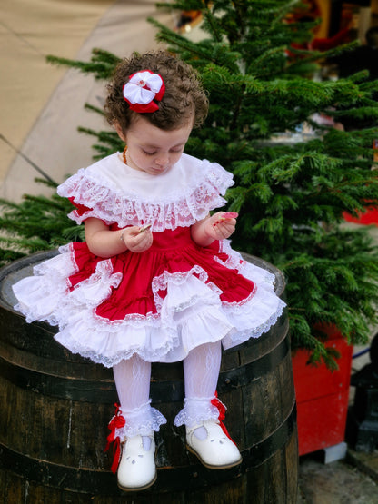 6-12 months. Red Lid'l Dolly with white bib and lace ruffles