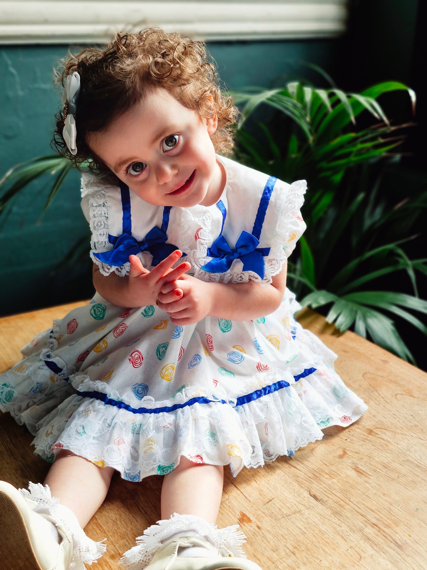 12-18 months. White Kotton Kandi dress with royal blue ribbon, lace and primary coloured prints