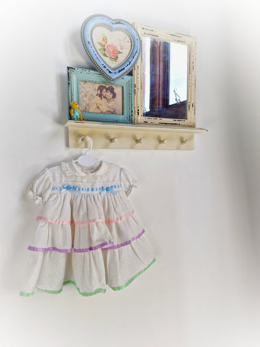 12 months. White dress with pastel ribbons and lace.
