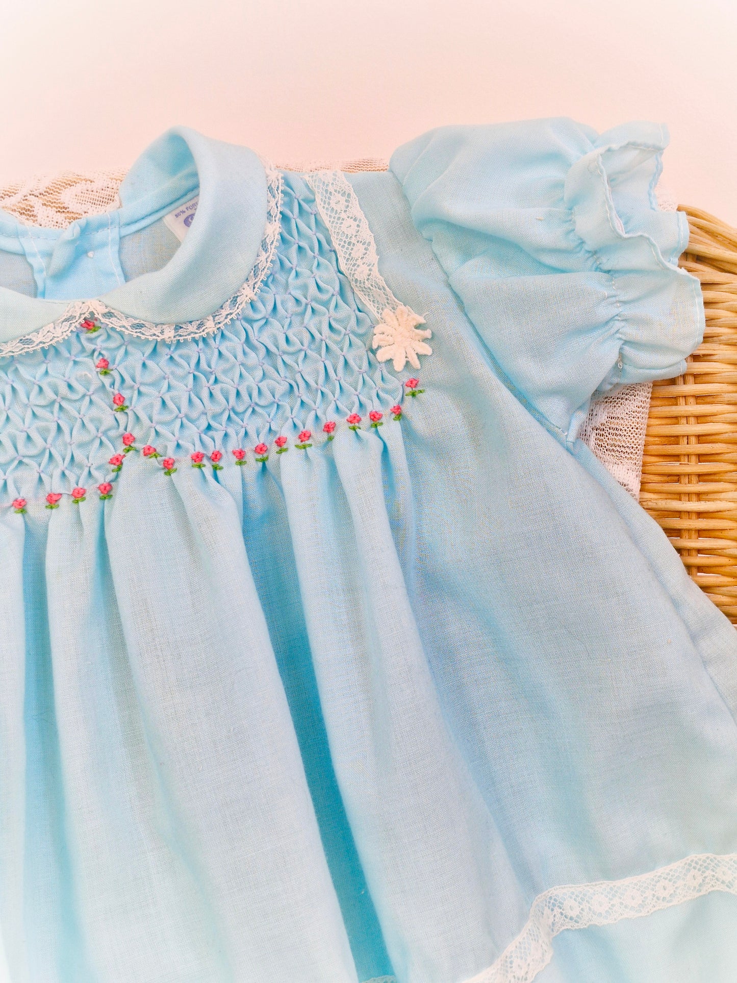 6-9 months. Blue smock dress with pink flowers and white lace details