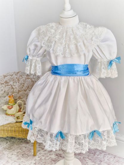 4-5 years. White satin dress with lace and blue ribbon