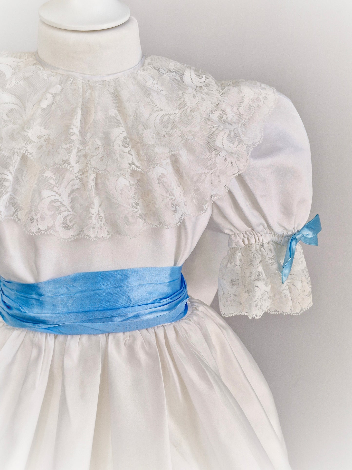 4-5 years. White satin dress with lace and blue ribbon