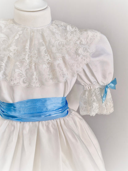 4-5 years. White satin dress with lace and blue ribbon