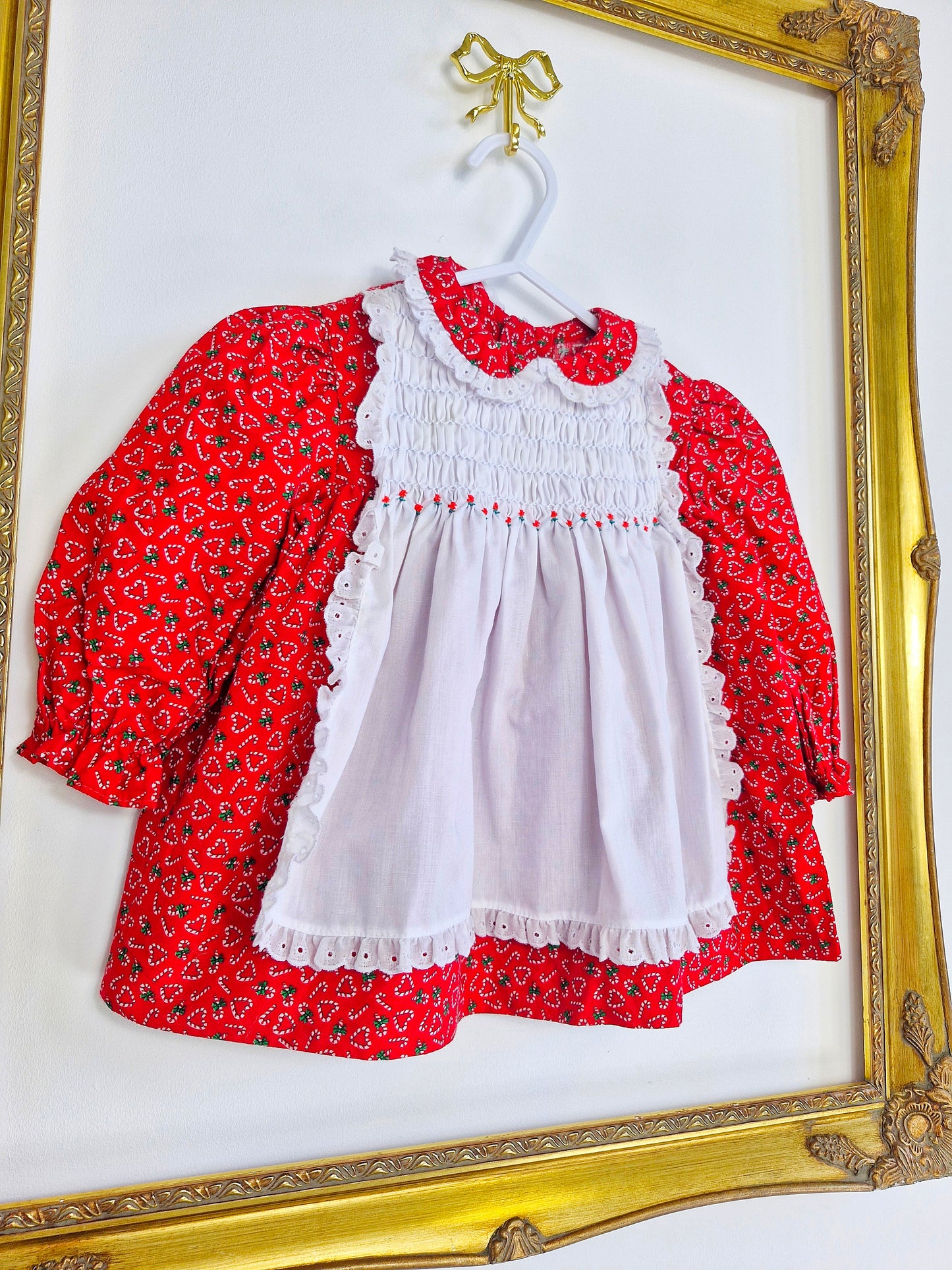9-12 months. Polly Flinders red dress with candy cane hearts and a white smocked pinny